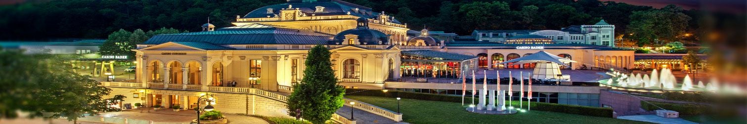 Beleuchtetes Kurhaus mit Casino und Springbrunnen in Baden-Baden am Abend.