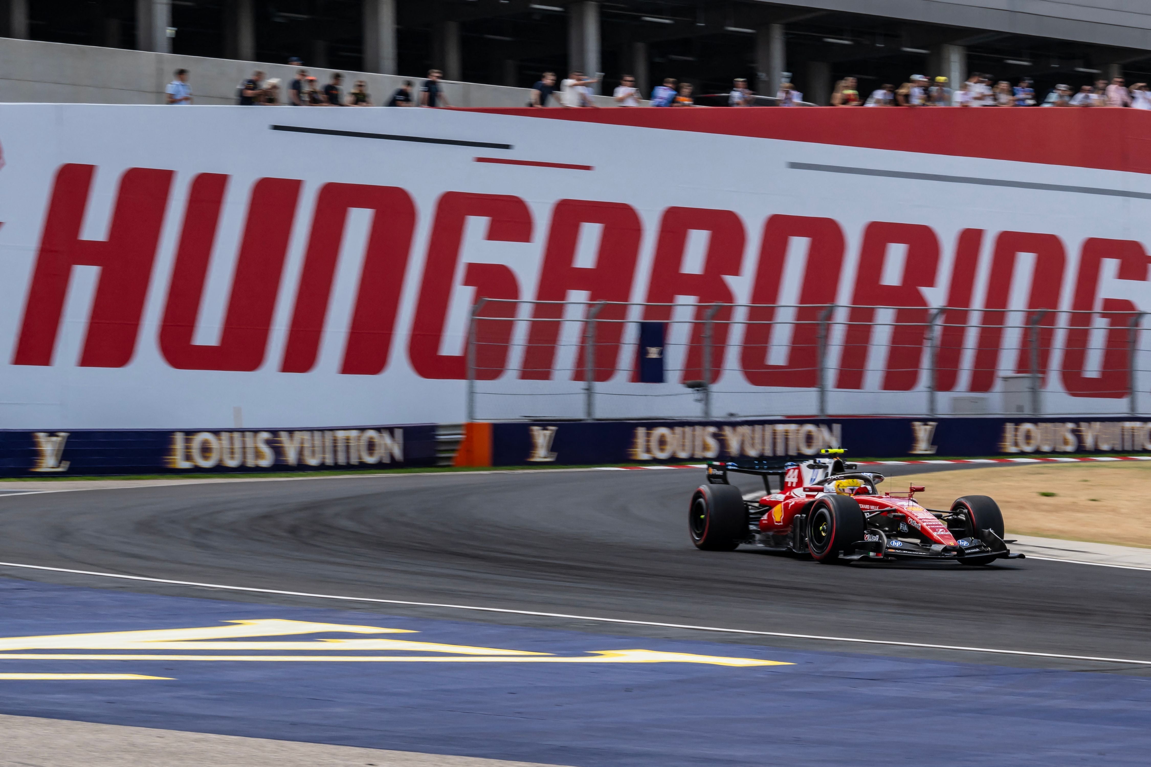 Ein roter Formel-1-Rennwagen von Ferrari fährt vor einer weißen Wand mit dem roten Schriftzug "HUNGARORING" durch eine Kurve.