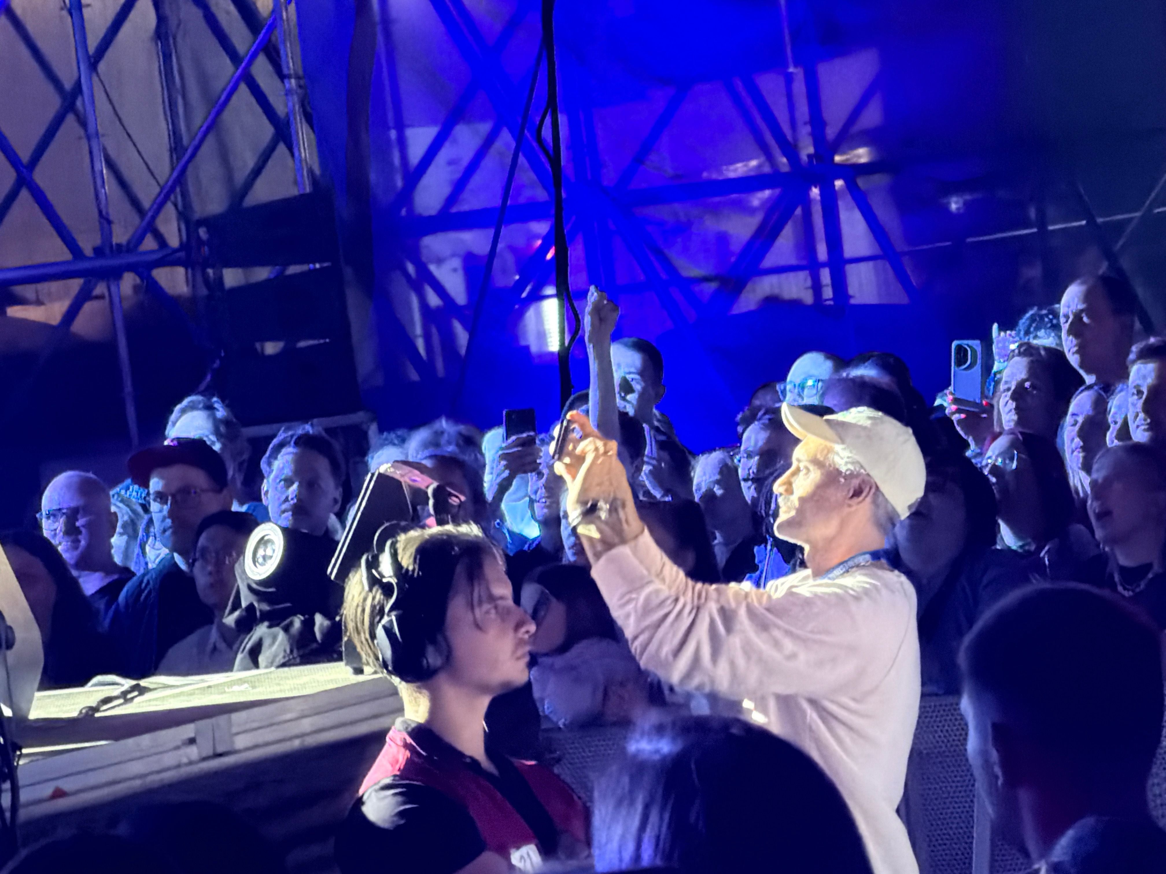 Menschenmenge auf einem Konzert, viele halten Smartphones in die Höhe, dunkle und blaue Beleuchtung.