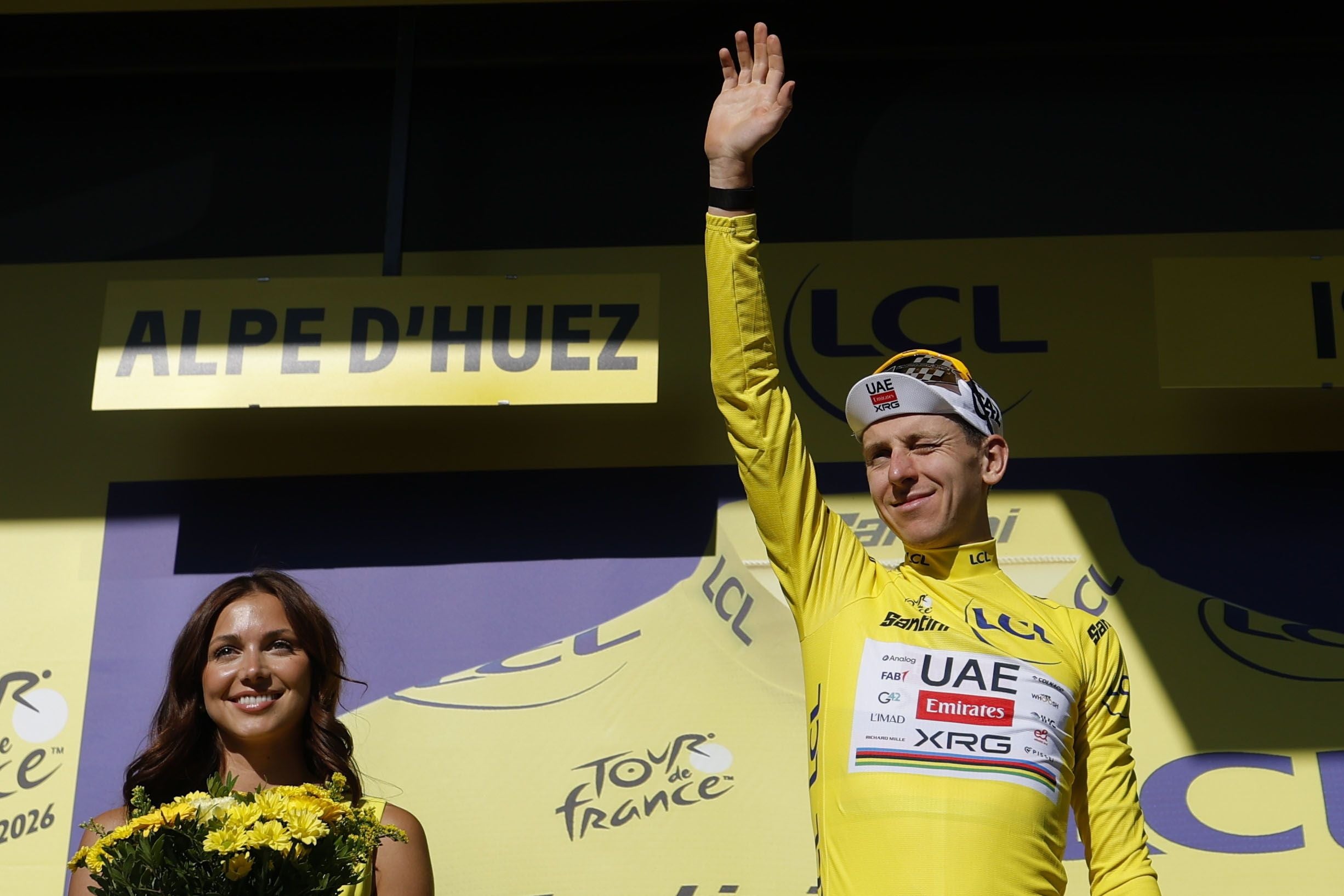 Tadej Pogacar im gelben Trikot jubelt auf dem Podium der Tour de France in Alpe d’Huez.