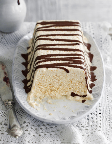 Eisblock auf einer Platte mit Schokoladensauce beträufelt, auf weißer Spitzenunterlage.