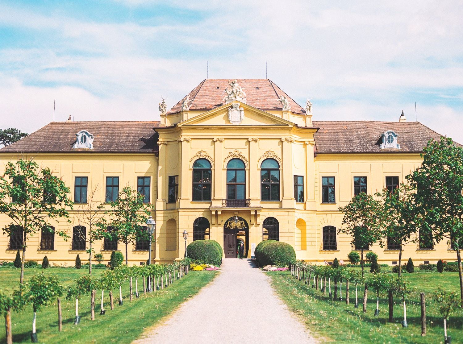 Gelbes Barockschloss Schloss Hof mit Garten und Weg, fotografiert bei Tageslicht.