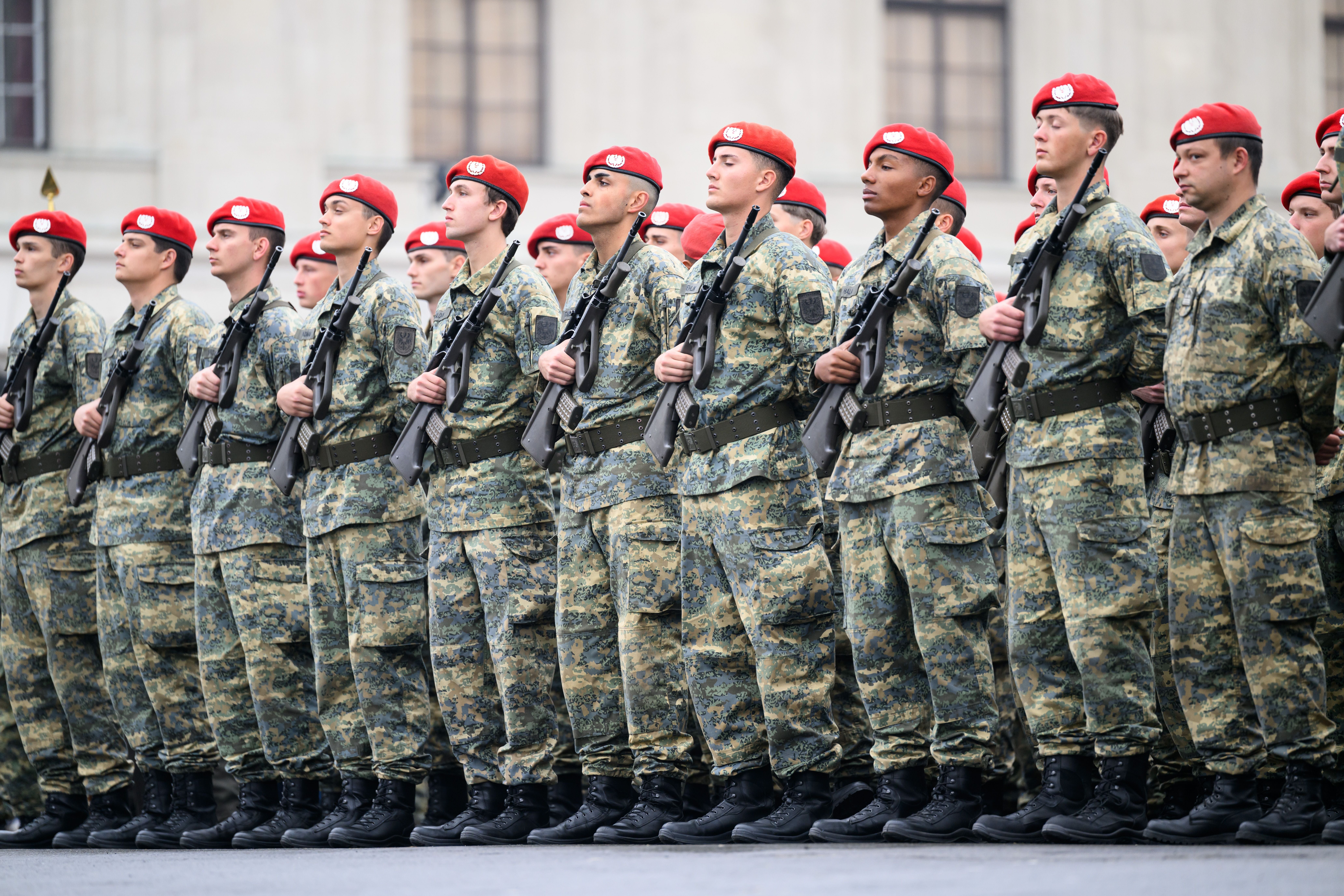 Österreichische Soldaten mit Gewehren und roten Baretten bei einer Parade am Heldenplatz in Wien.