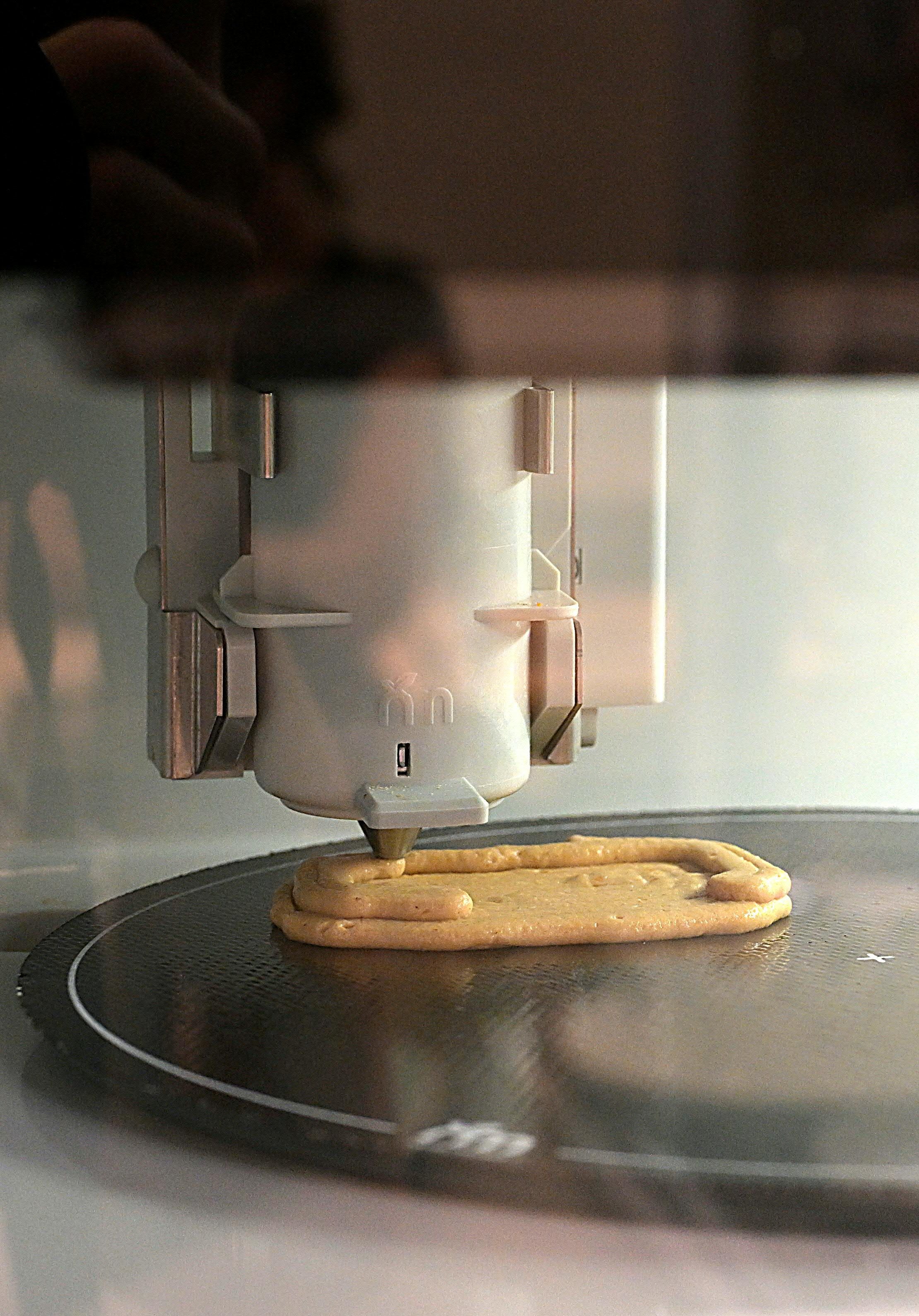 Ein 3D-Drucker stellt mundgerechte Lebensmittel auf einer Platte her.