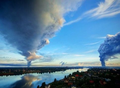 Große Rauchwolken steigen über einer Stadt mit Fluss bei Sankt Petersburg in den Himmel.