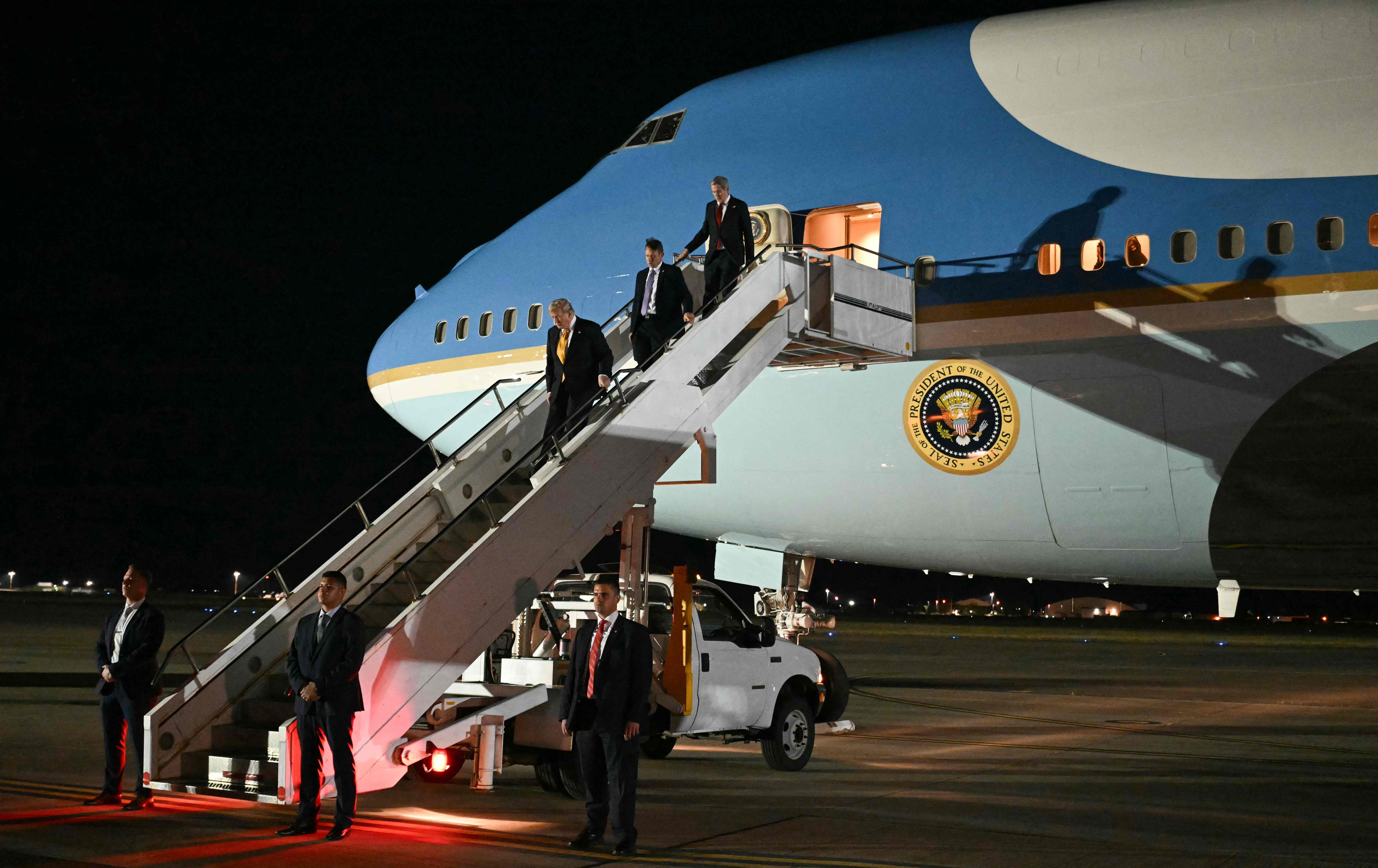 Männer steigen nachts eine Flugzeugtreppe von Air Force One mit US-Präsidentensiegel hinab.