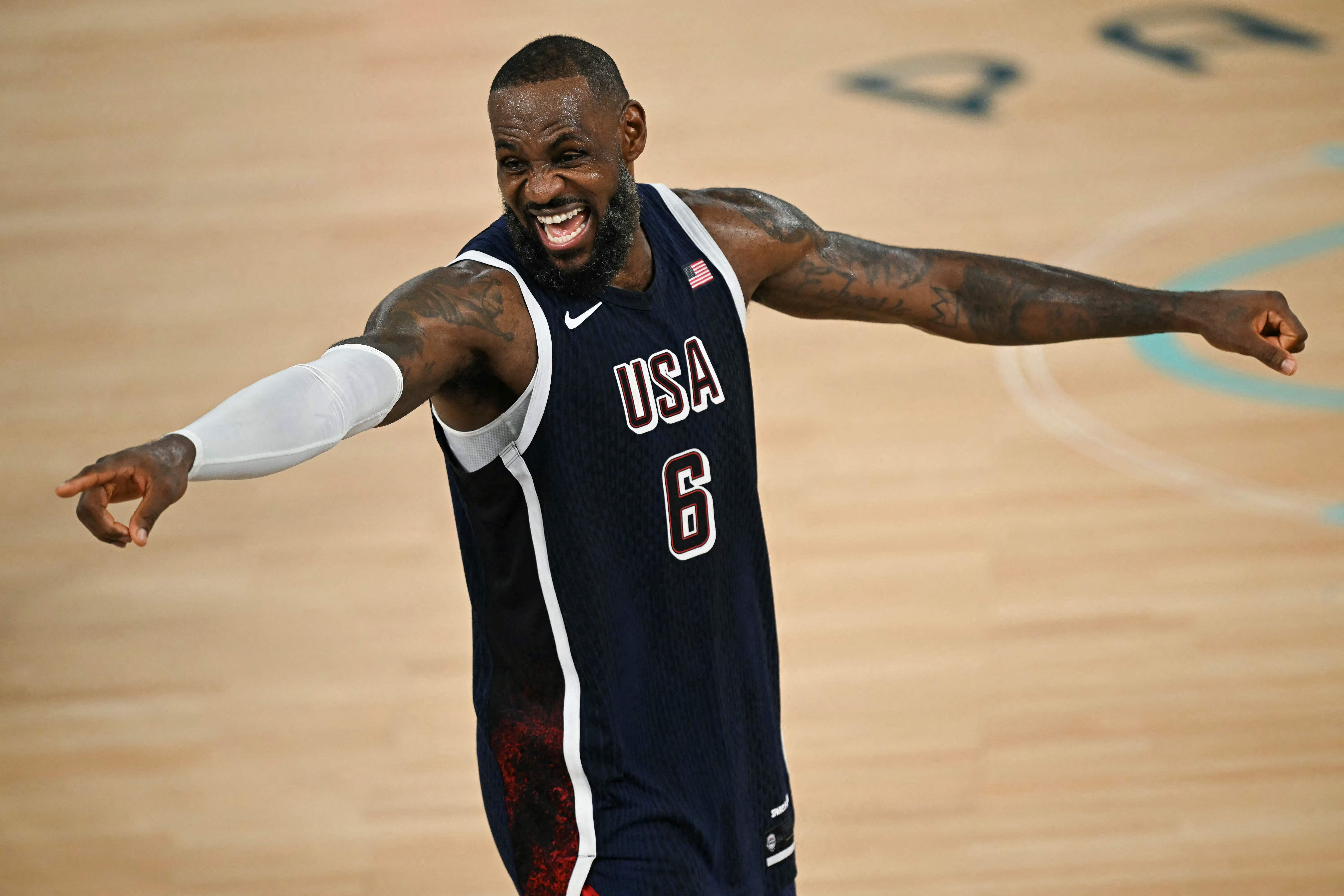 Ein Basketballspieler im USA-Trikot jubelt mit ausgestreckten Armen auf dem Spielfeld.