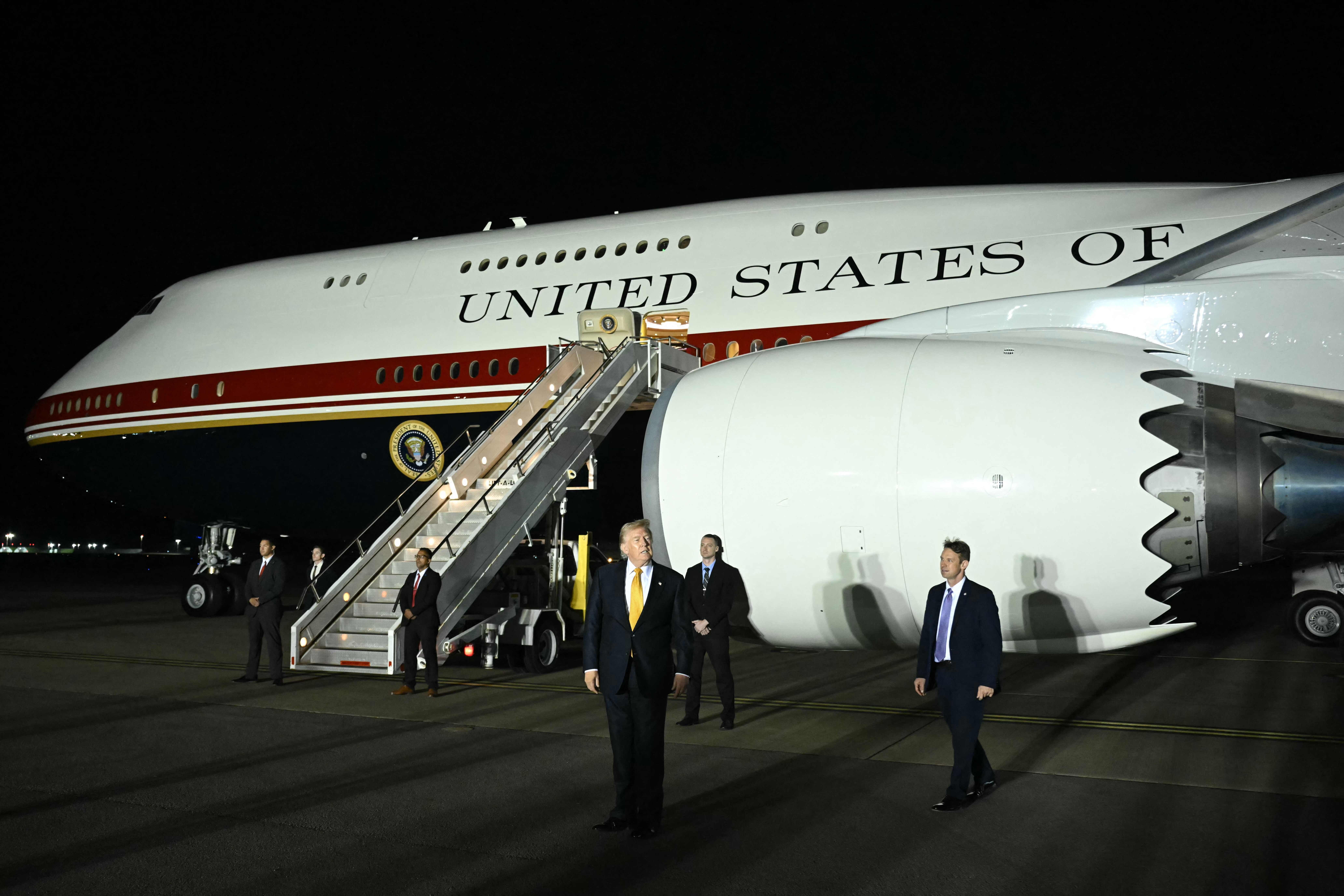 Mehrere Personen stehen nachts vor der Air Force One auf einem Flughafen.
