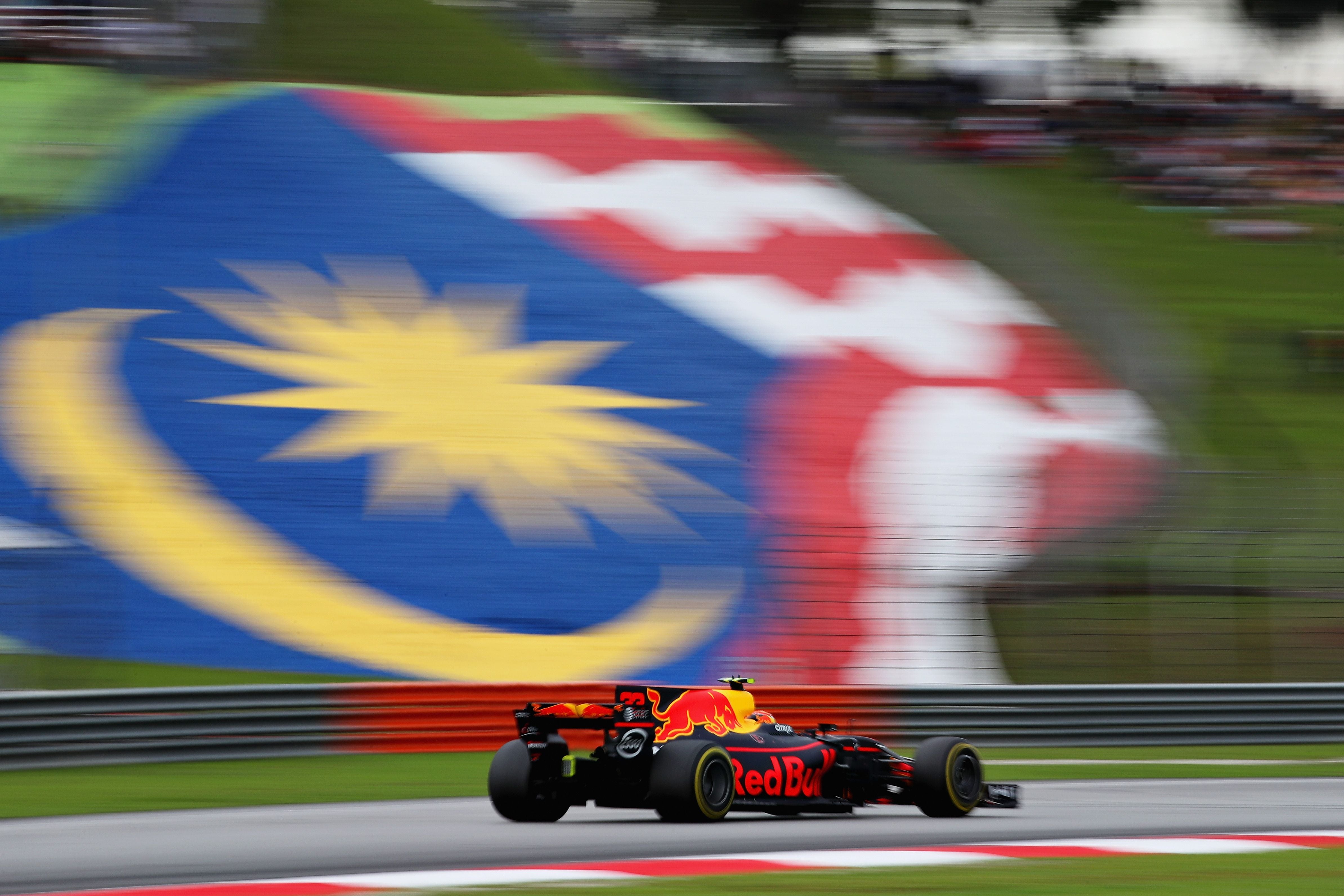 Ein Red Bull Formel-1-Wagen fährt vor einer großen malaysischen Flagge auf der Rennstrecke.