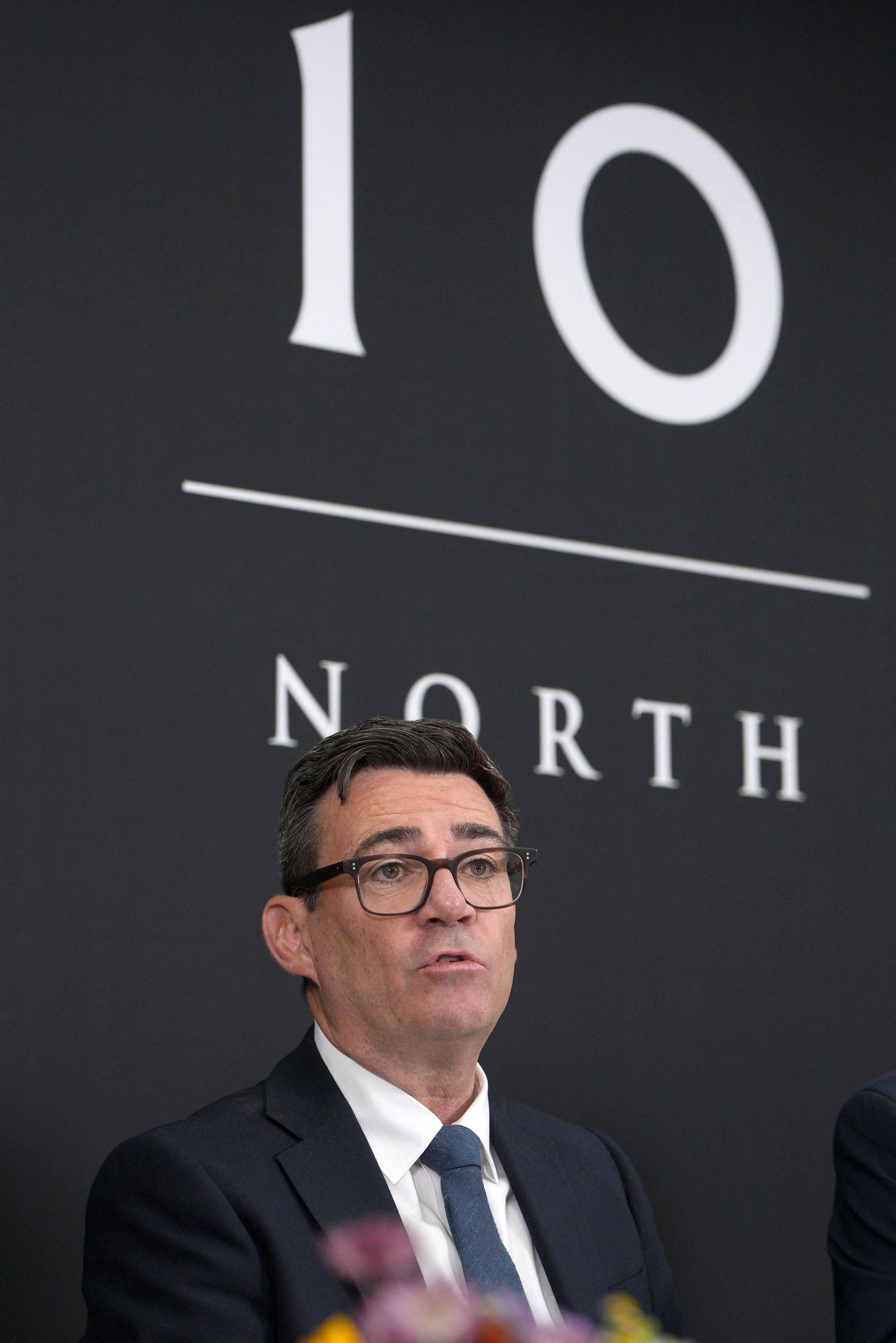 Ein Mann im Anzug spricht vor einer Wand mit der Aufschrift „10 North“.