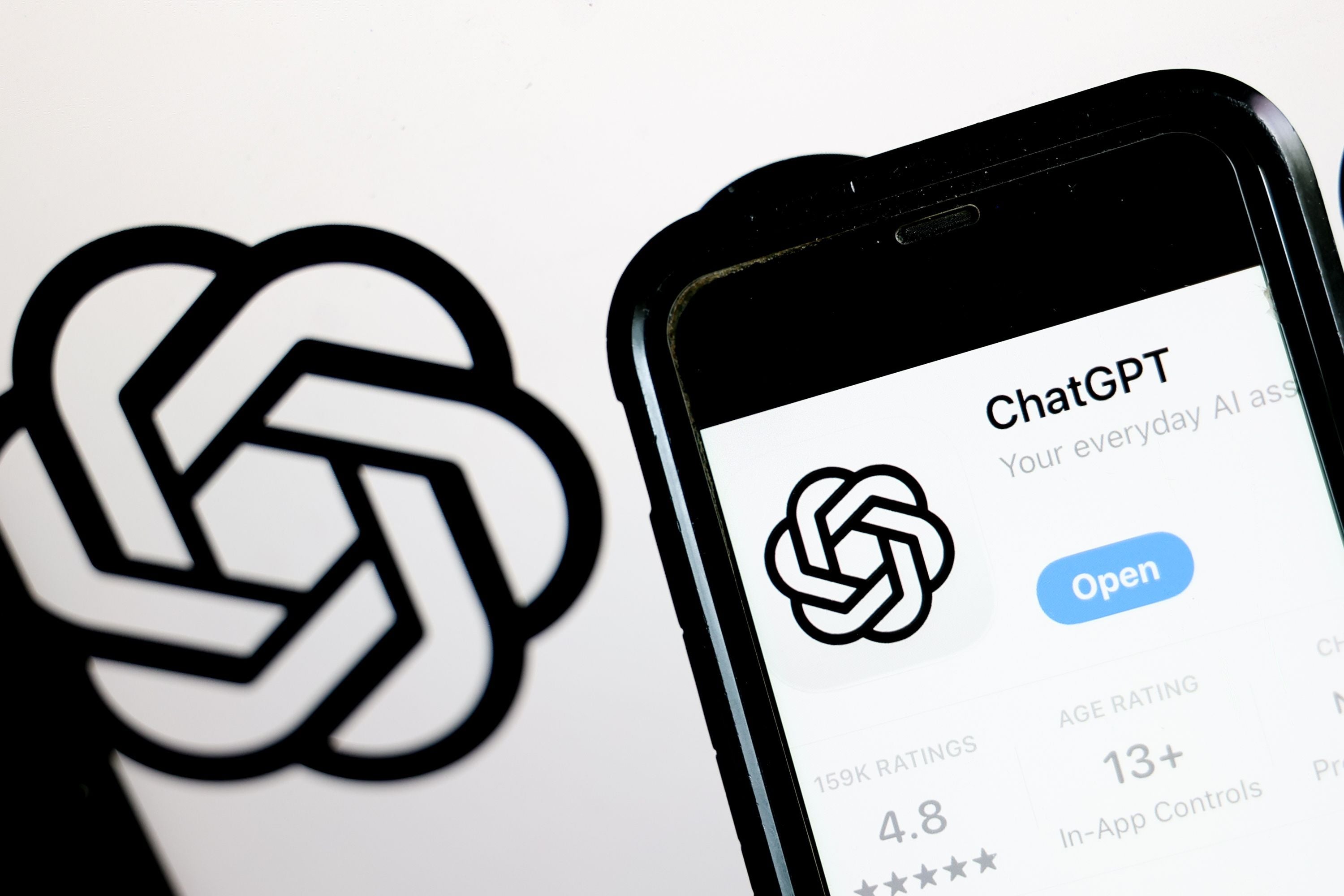 ChatGPT-App mit Logo auf Smartphone-Bildschirm, daneben das große ChatGPT-Logo.