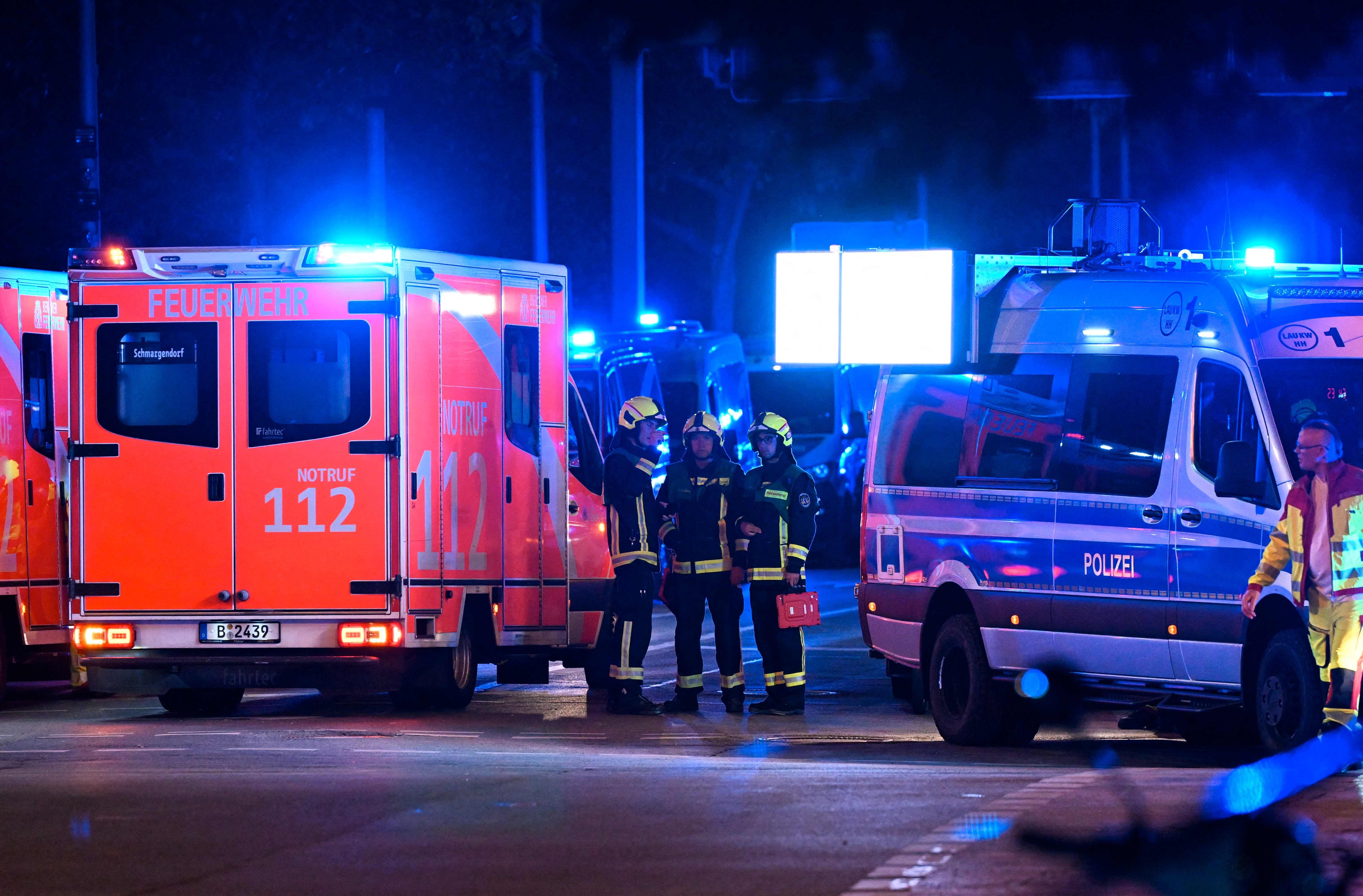 Mehrere Einsatzfahrzeuge und Rettungskräfte an einem beleuchteten Unfallort bei Nacht.