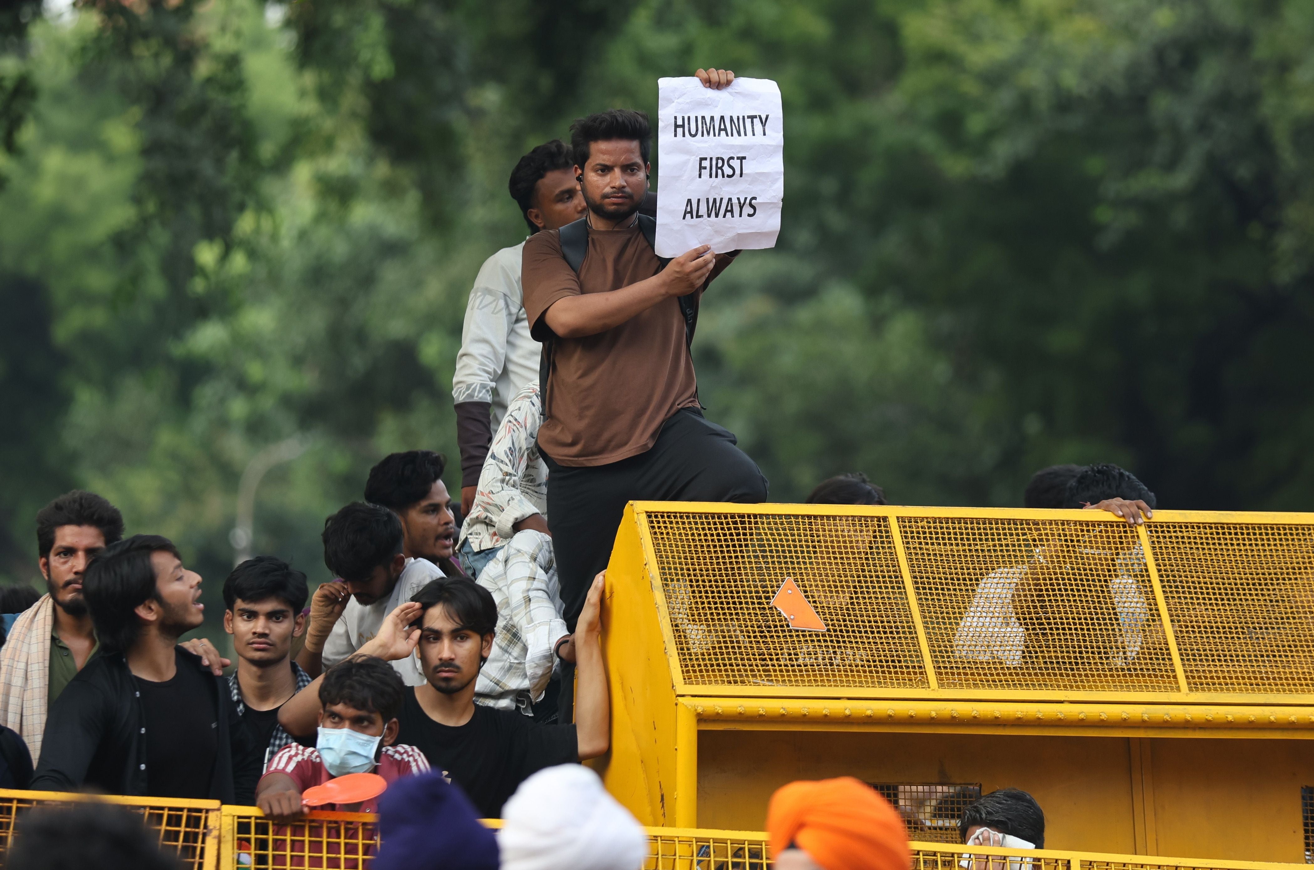 Ein Mann hält ein Schild mit „Humanity First Always“ bei einer Protestkundgebung hoch.