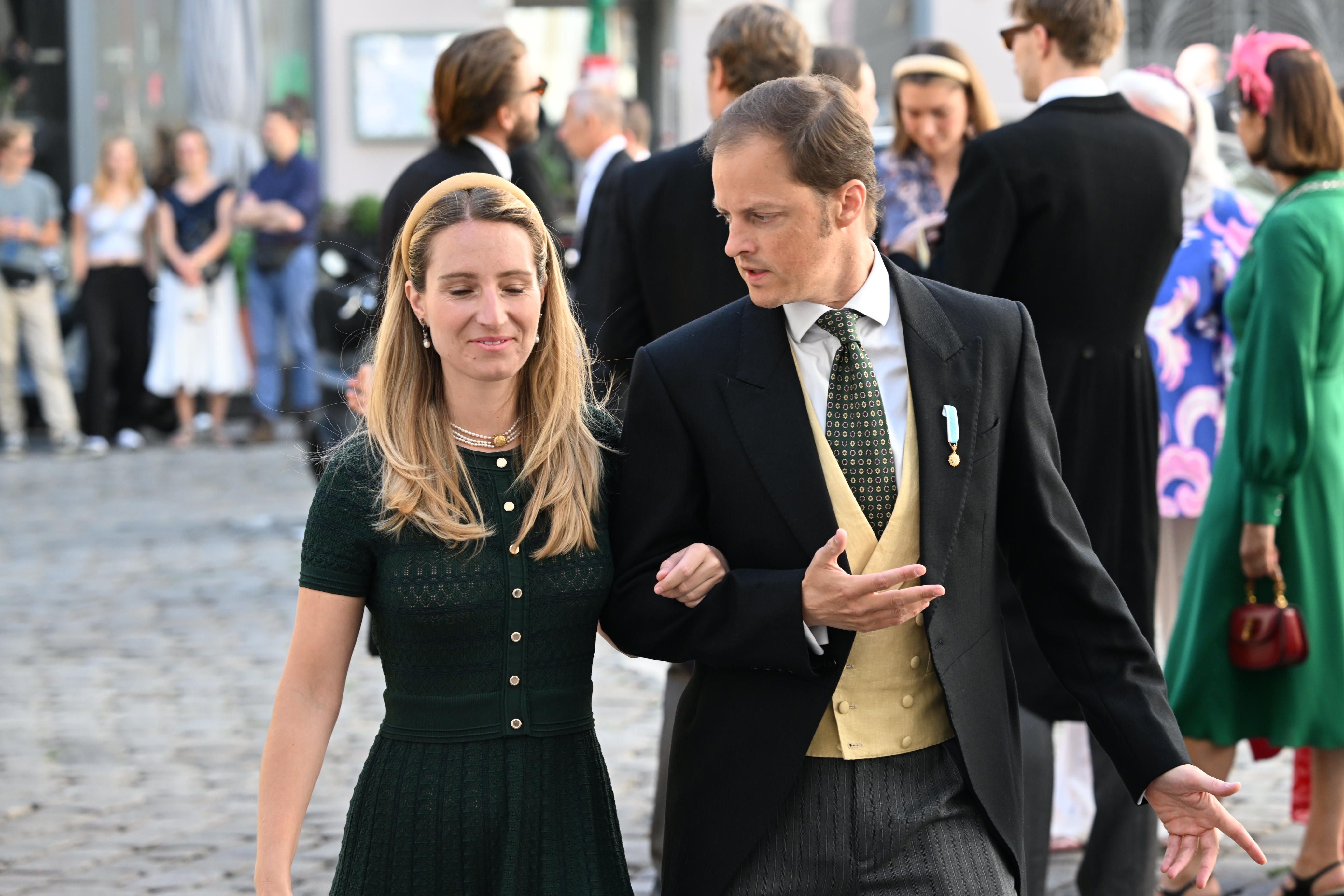 Ein Paar in festlicher Kleidung geht Arm in Arm bei einer Hochzeit im Freien.