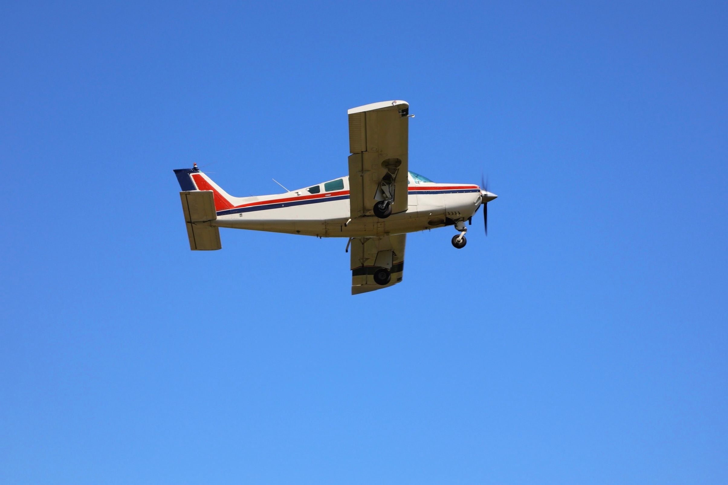 Ein Kleinflugzeug fliegt am klaren, blauen Himmel.