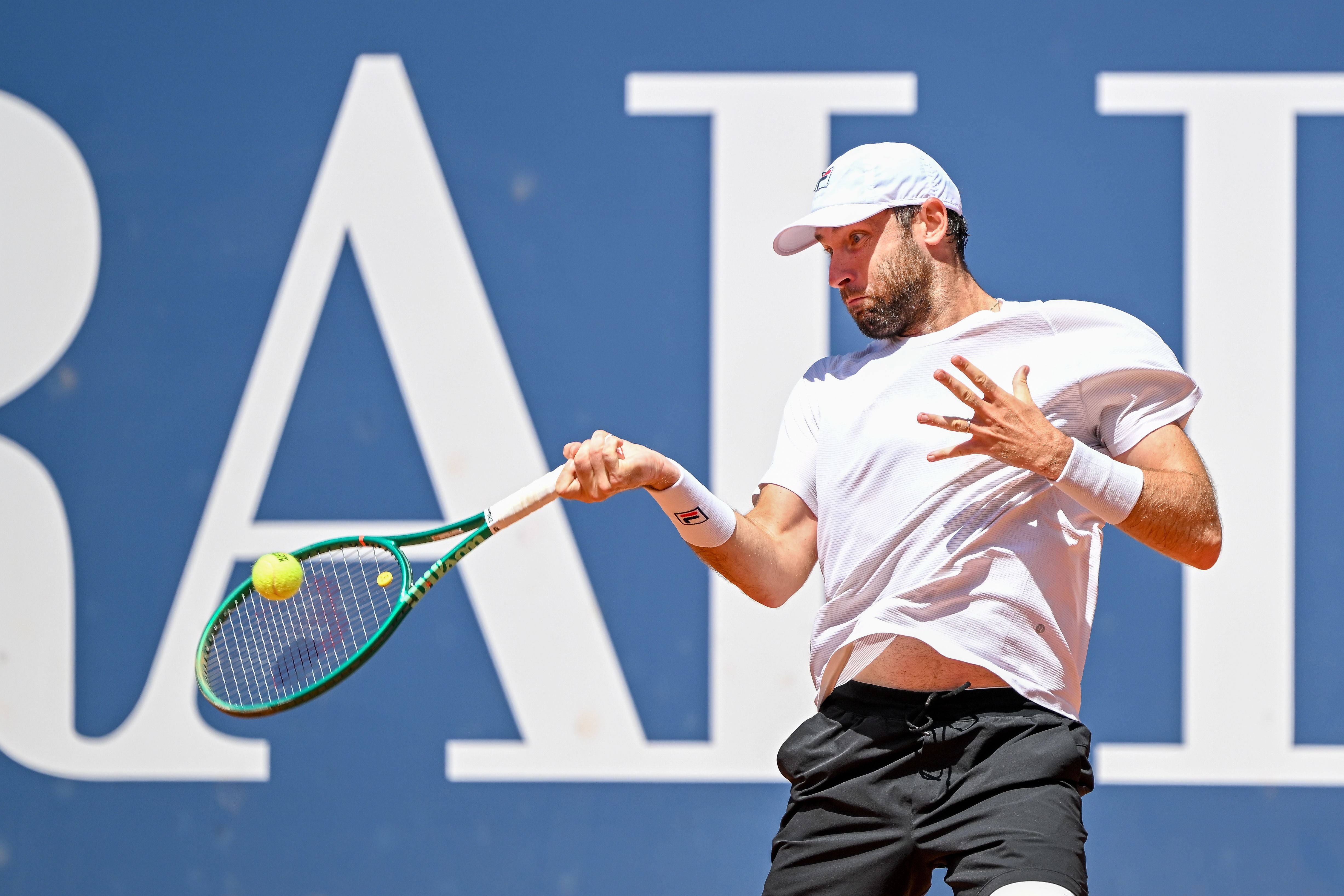 Tennisspieler schlägt den Ball mit einem Vorhandschlag auf Sandplatz.