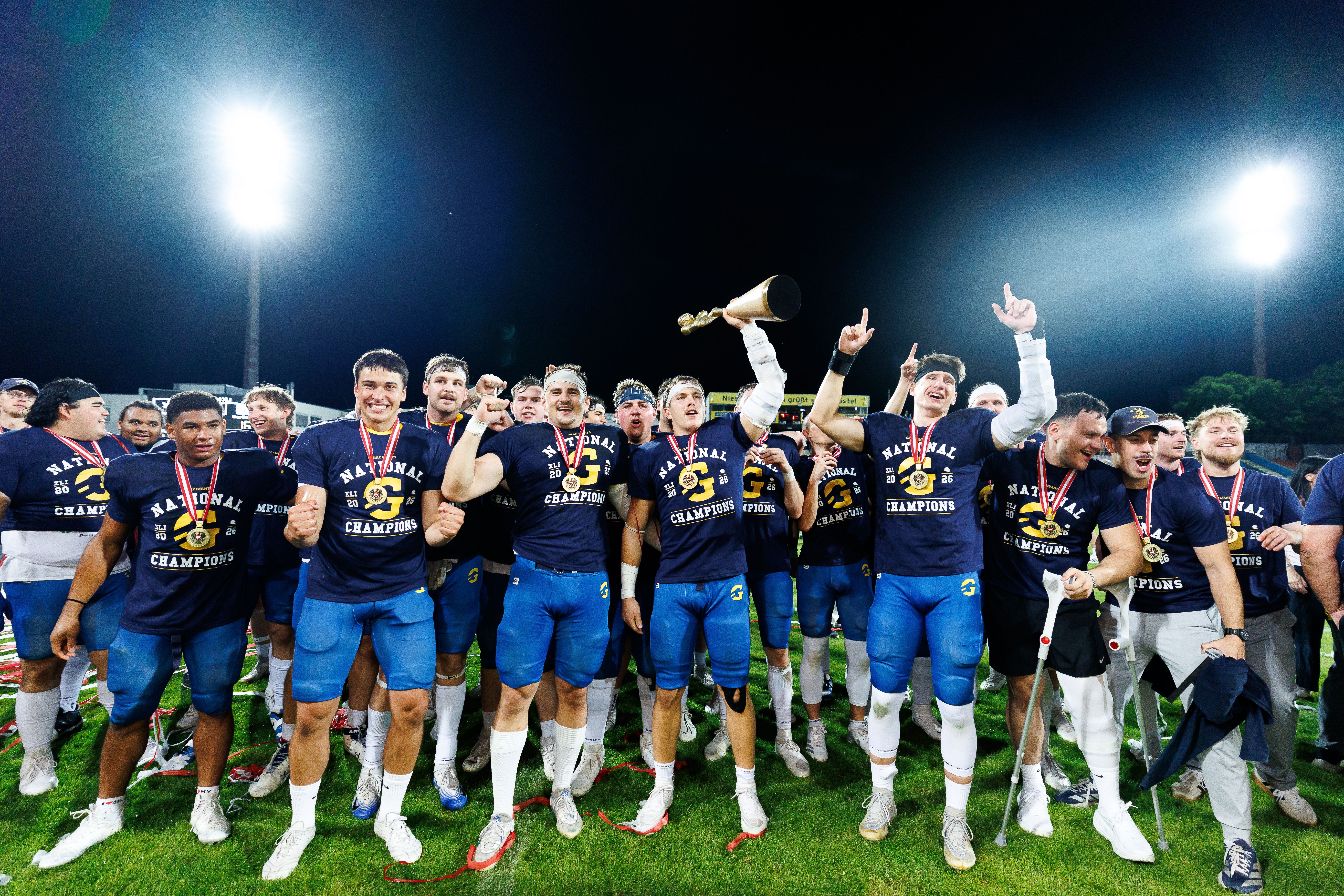 Die Graz Giants jubeln mit Medaillen und Pokal nach dem Gewinn der Austrian Bowl XLI 2026.