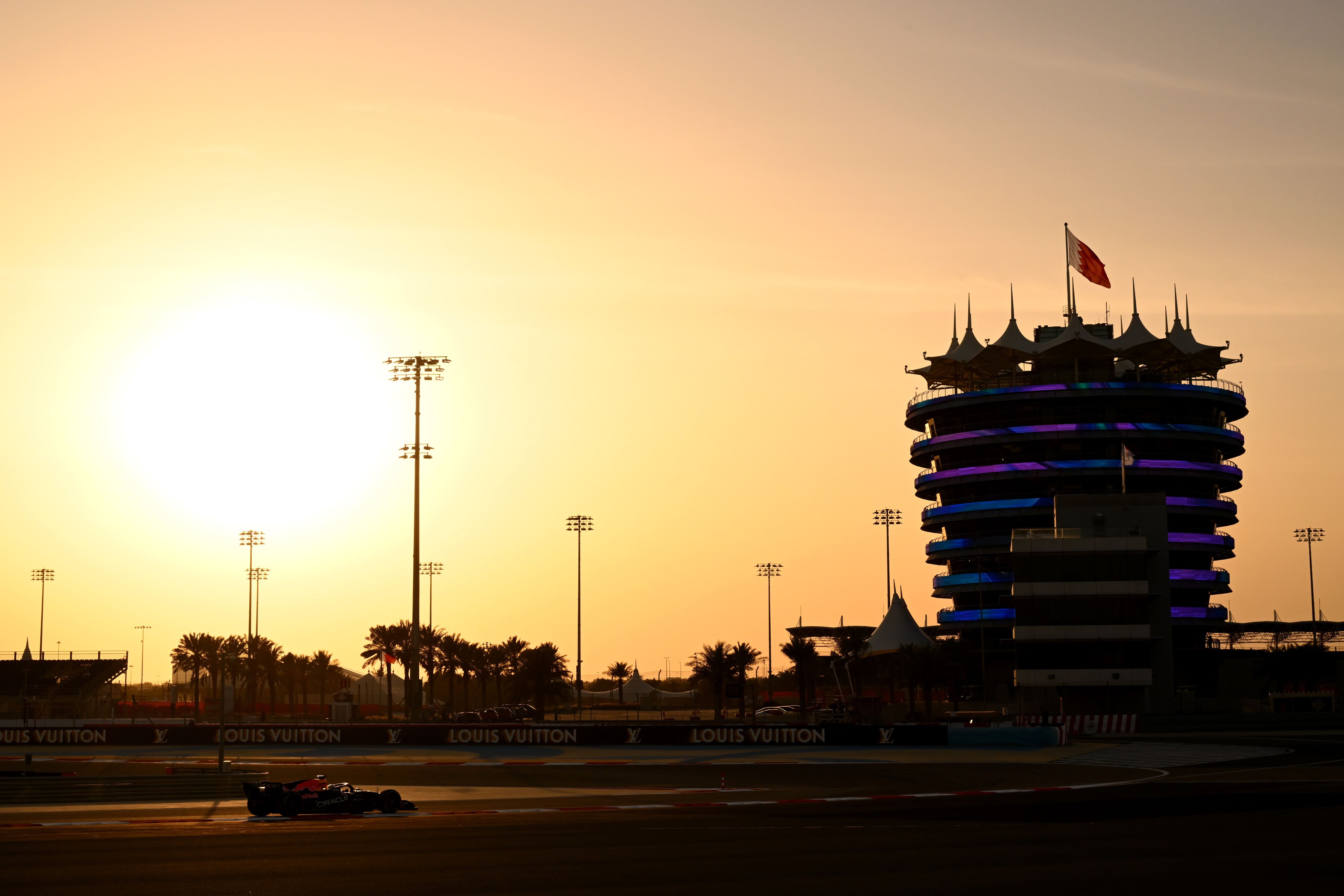 Formel-1-Auto fährt bei Sonnenuntergang am Bahrain International Circuit vorbei.