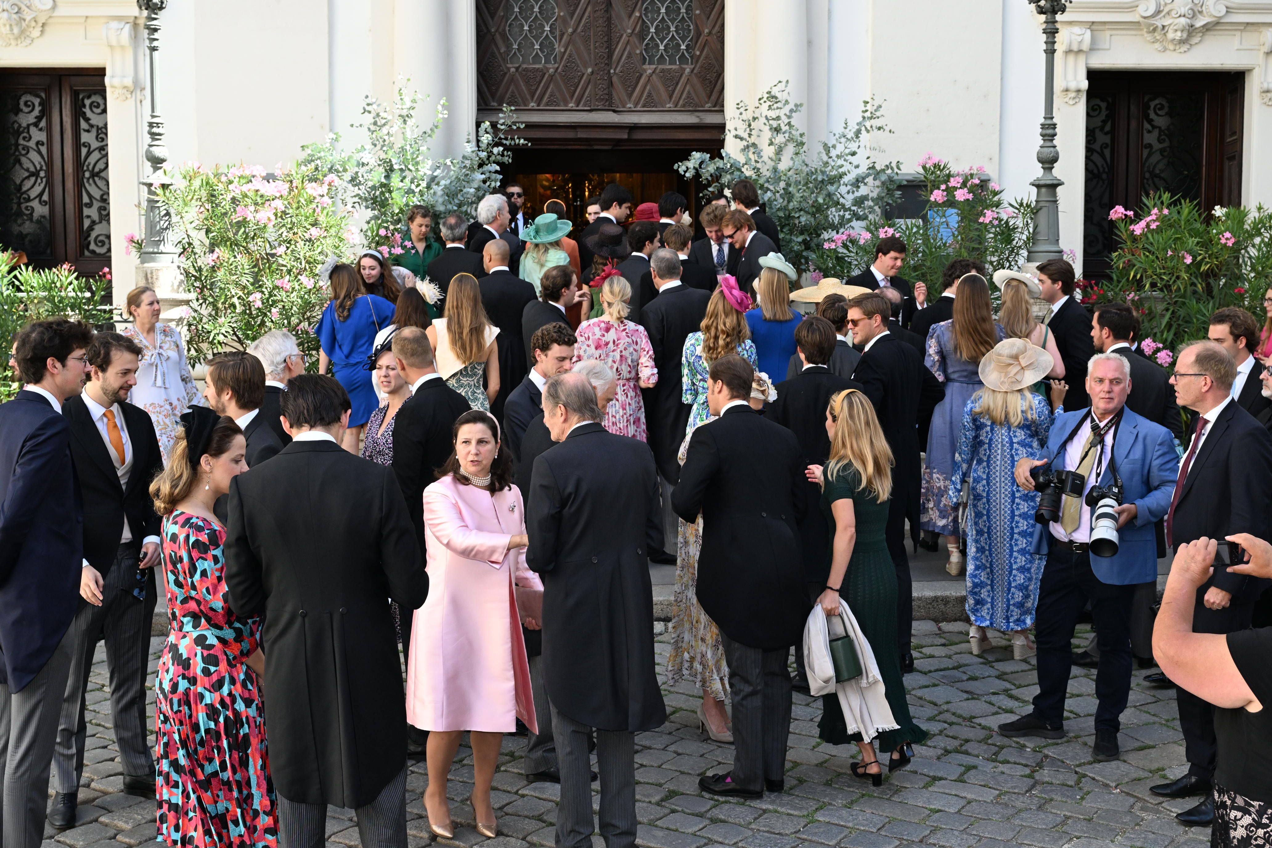 Viele elegant gekleidete Gäste versammeln sich vor dem Eingang einer Kirche zur Hochzeit.