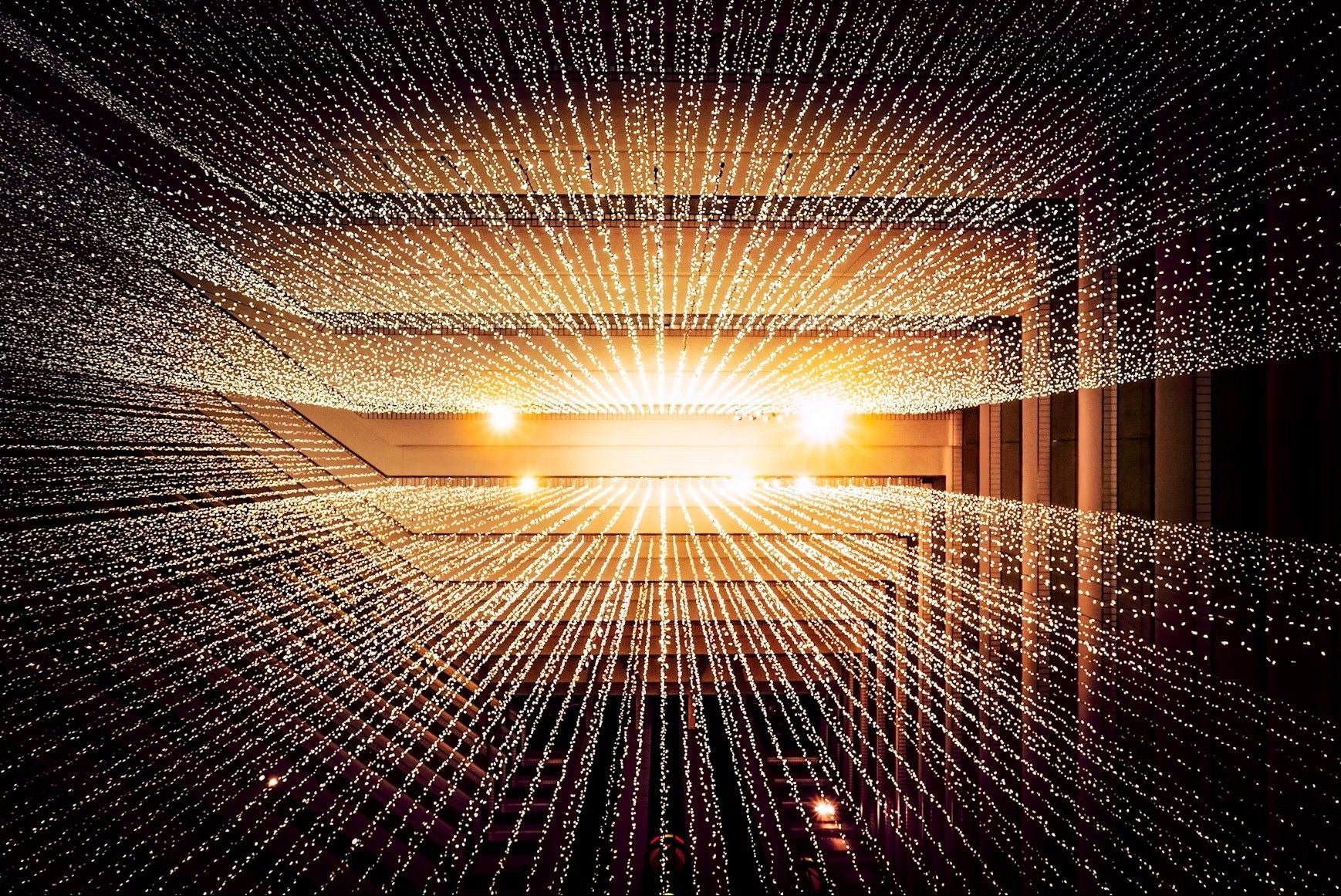Viele Lichtpunkte strahlen von einem zentralen Punkt in einem Rechenzentrum aus.