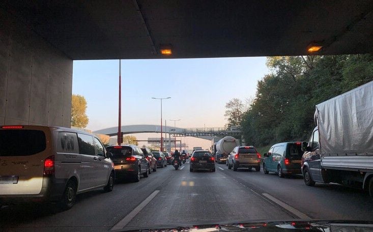 Autos und Lastwagen stehen im Stau auf der A23 unter einer Brücke bei Tageslicht.