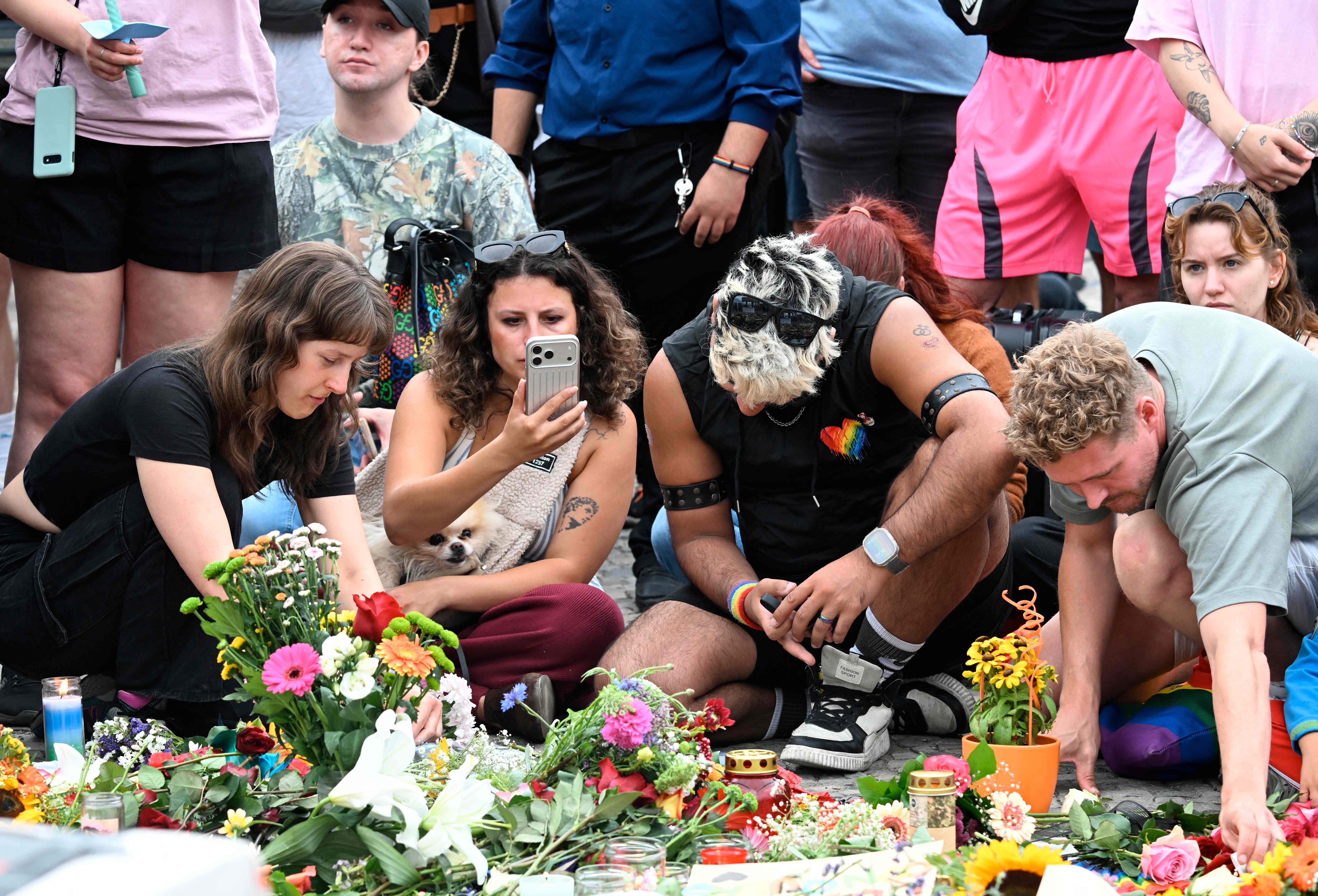 Menschen trauern gemeinsam und legen Blumen am Brandenburger Tor nieder.