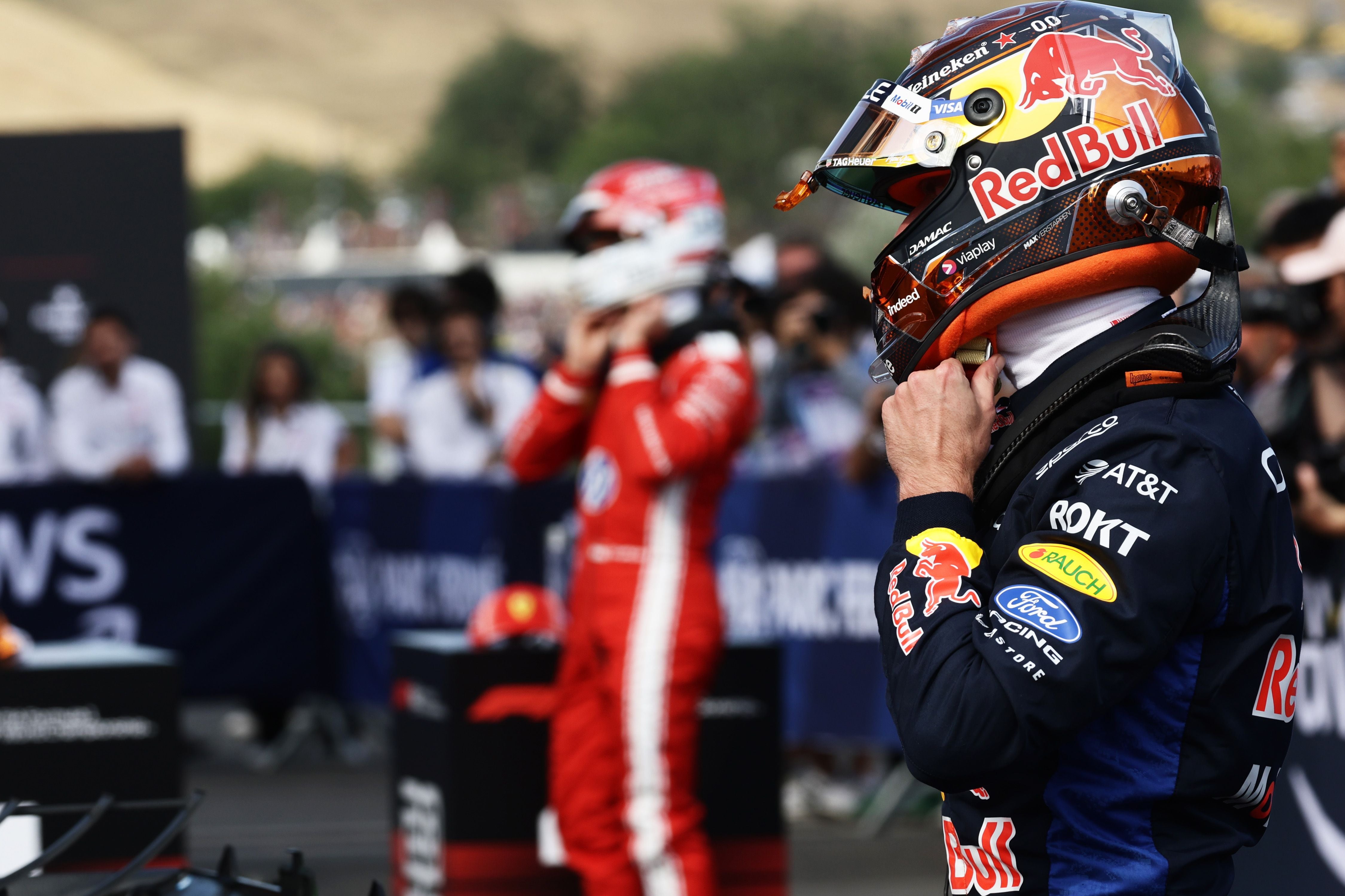 Ein Red-Bull-Formel-1-Fahrer steht im Parc Fermé und zieht seinen Helm zurecht.