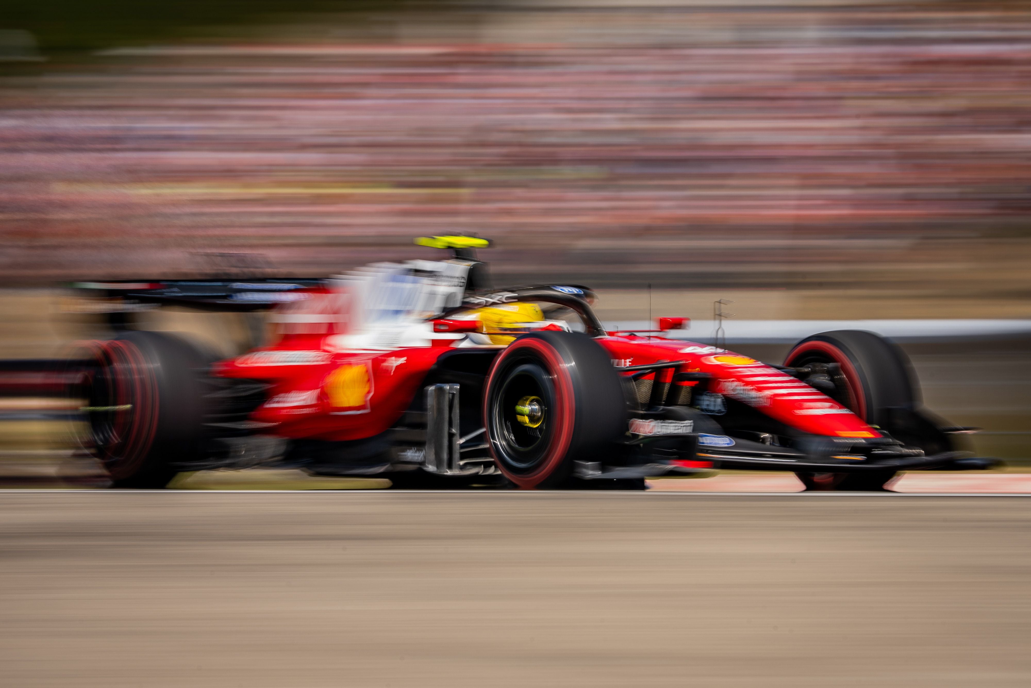 Ein roter Formel-1-Rennwagen fährt schnell über die Rennstrecke, unscharfer Hintergrund.