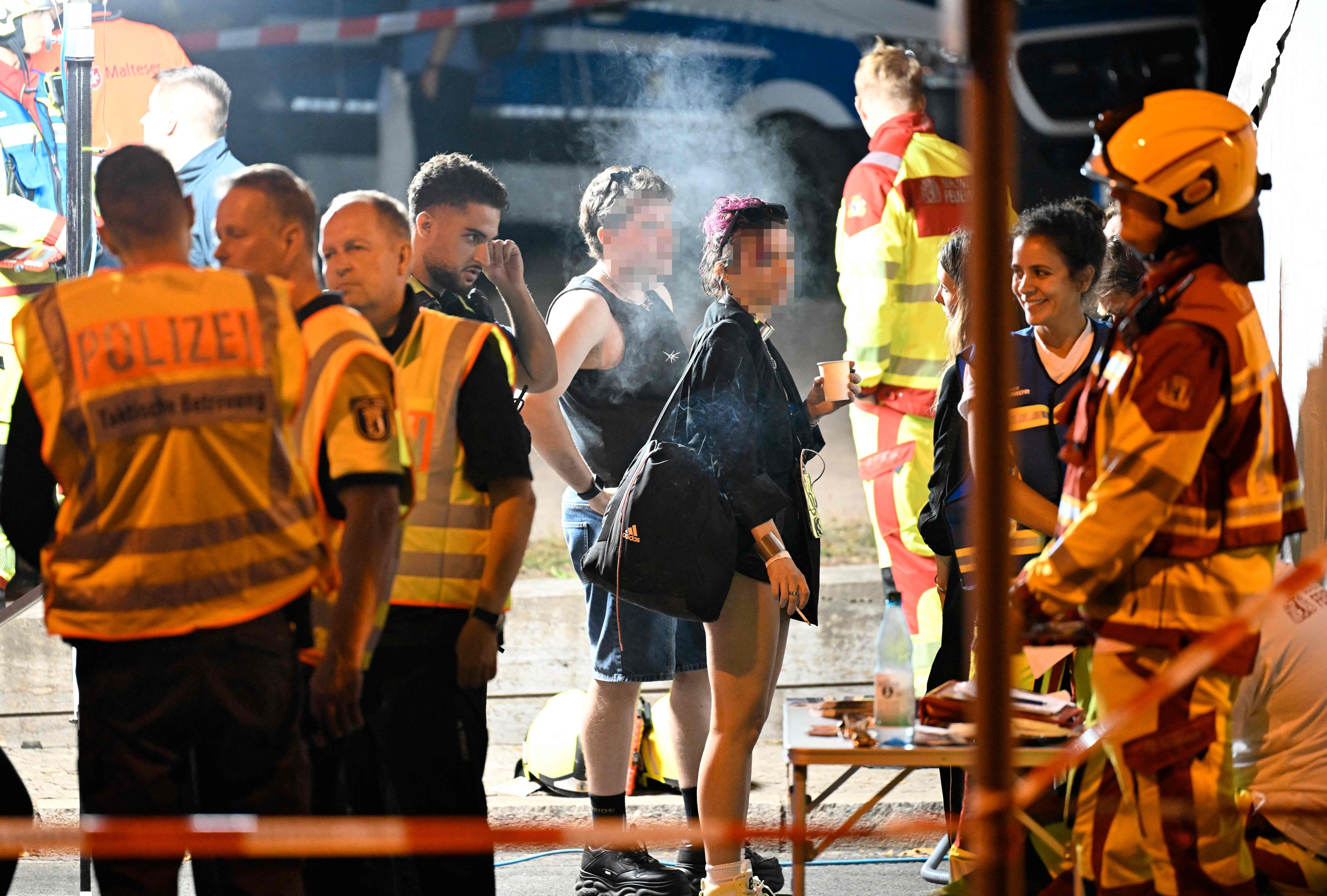 Polizei, Rettungskräfte und CSD-Teilnehmende an einem abgesperrten Unfallort in Berlin bei Nacht.