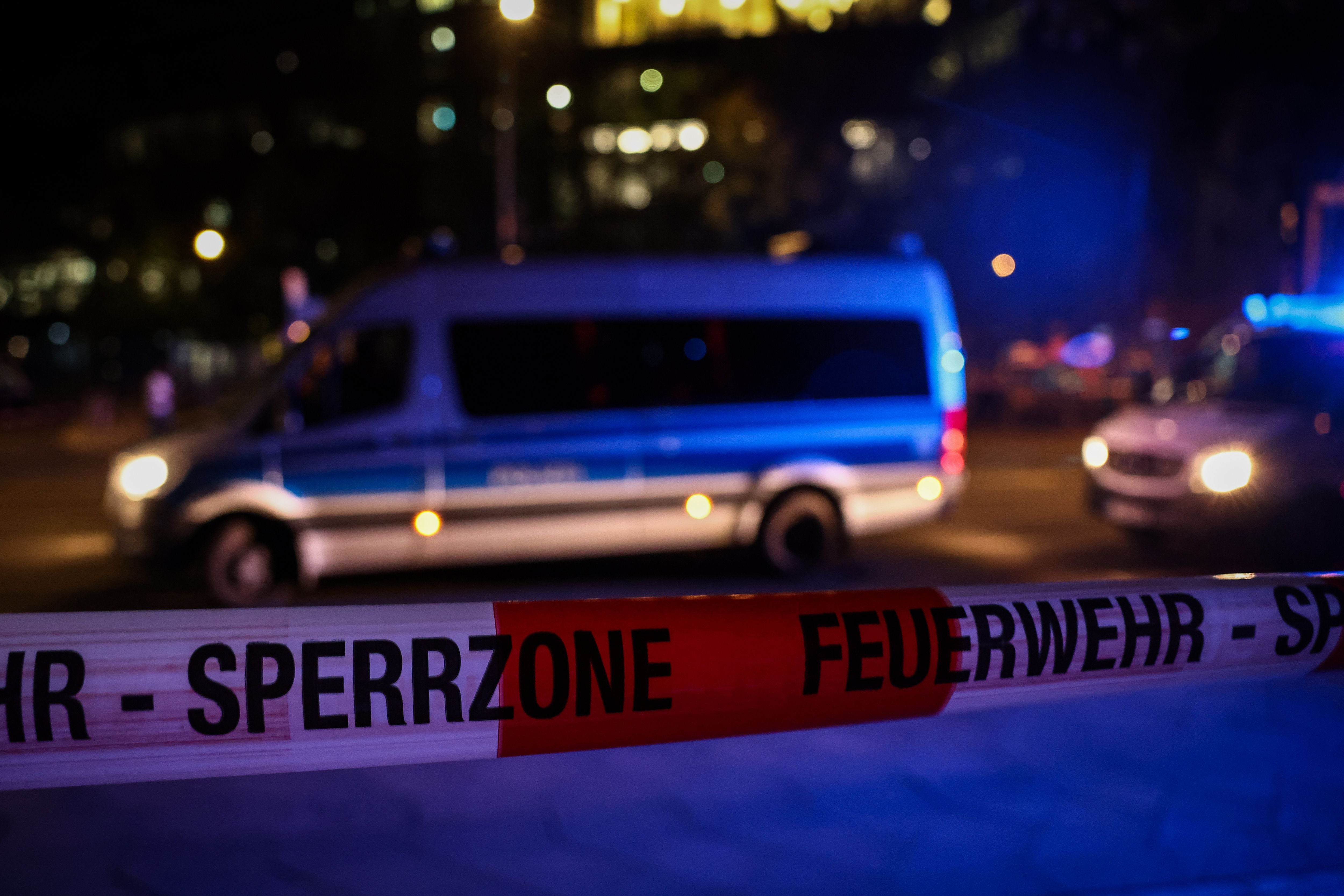 Absperrband der Feuerwehr vor Polizei- und Einsatzfahrzeugen bei Nacht in Berlin.