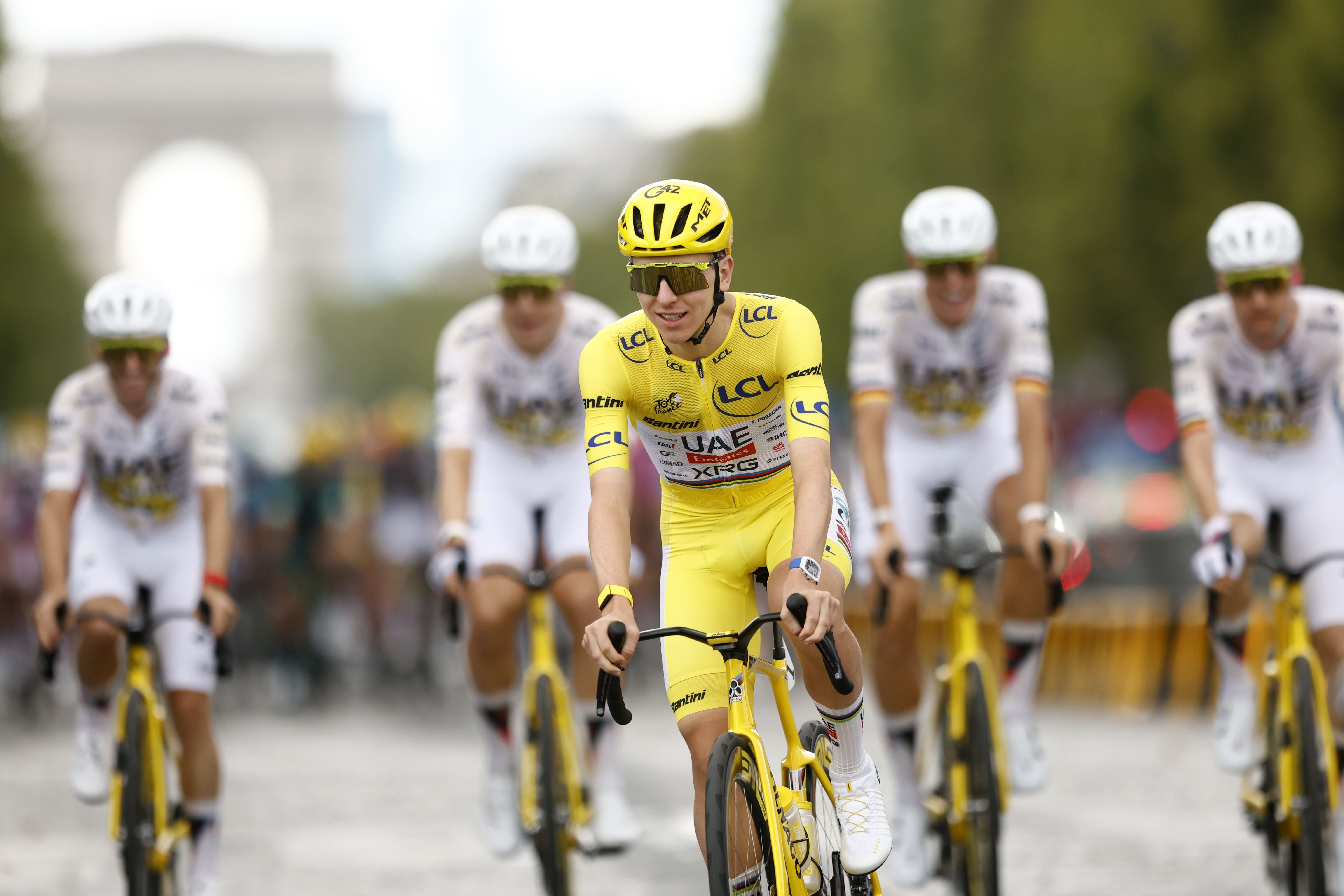 Radfahrer im gelben Trikot fährt mit Teamkollegen auf den Champs-Elysées während der Tour de France.