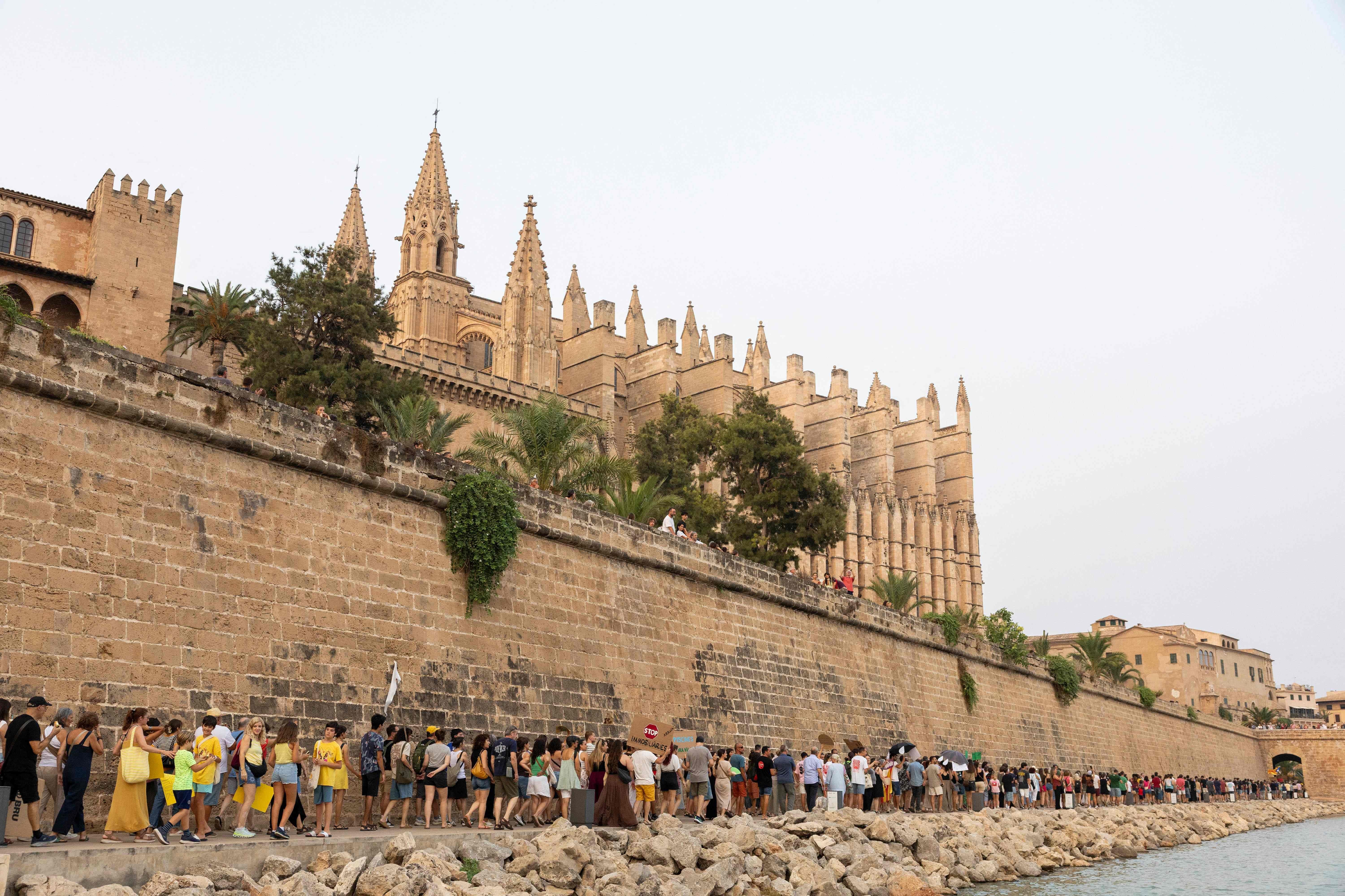 Viele Menschen protestieren entlang einer Mauer vor der Kathedrale von Palma de Mallorca.