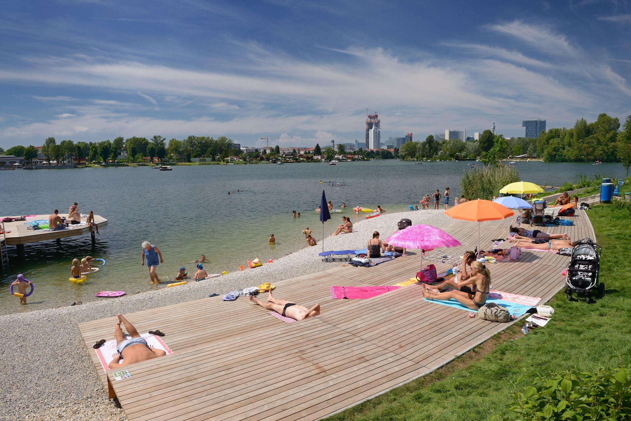 Menschen entspannen und baden an einem sonnigen Sommertag am Ufer der Donau in Wien.