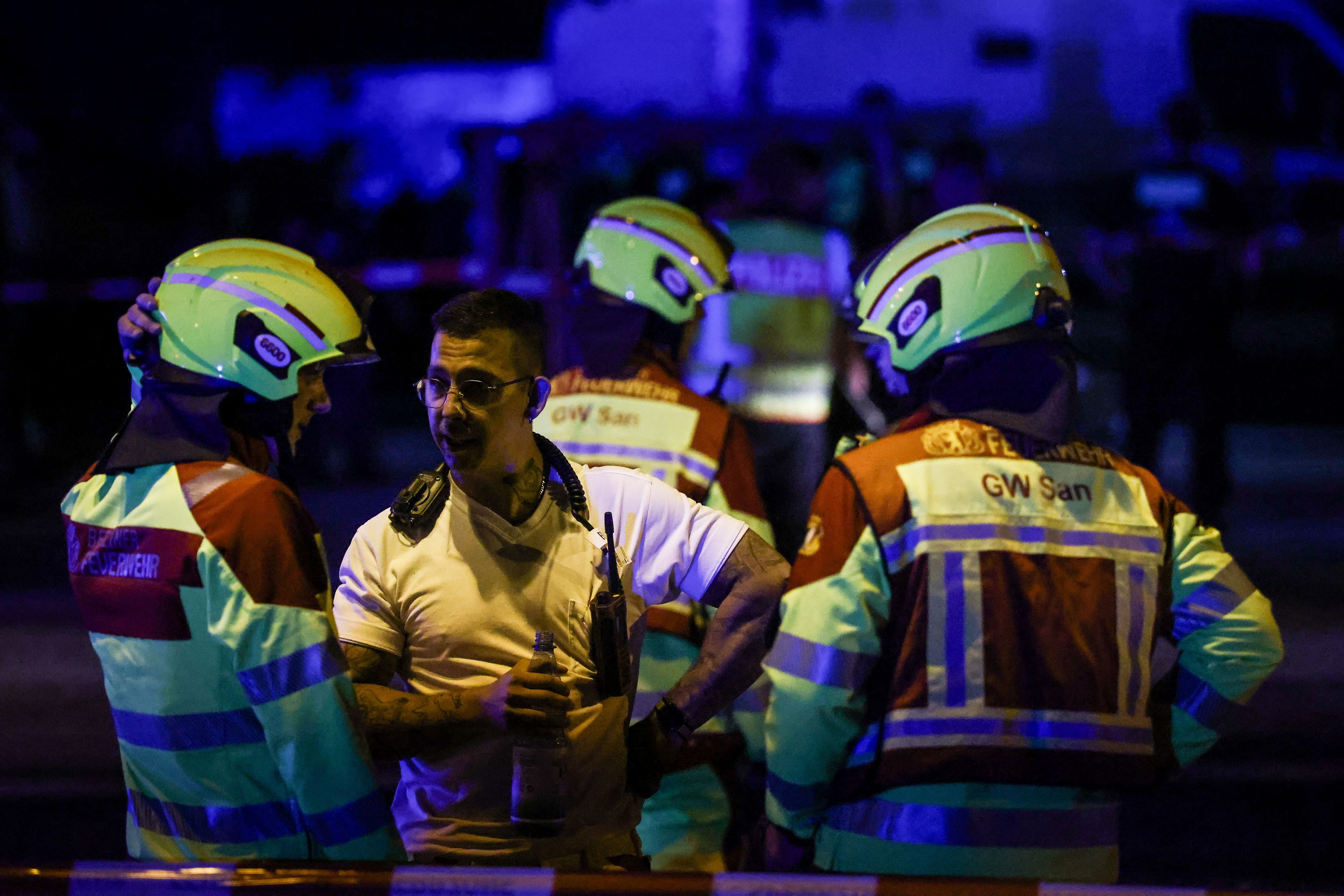Einsatzkräfte der Feuerwehr sprechen nachts miteinander bei einem Einsatz in Berlin.