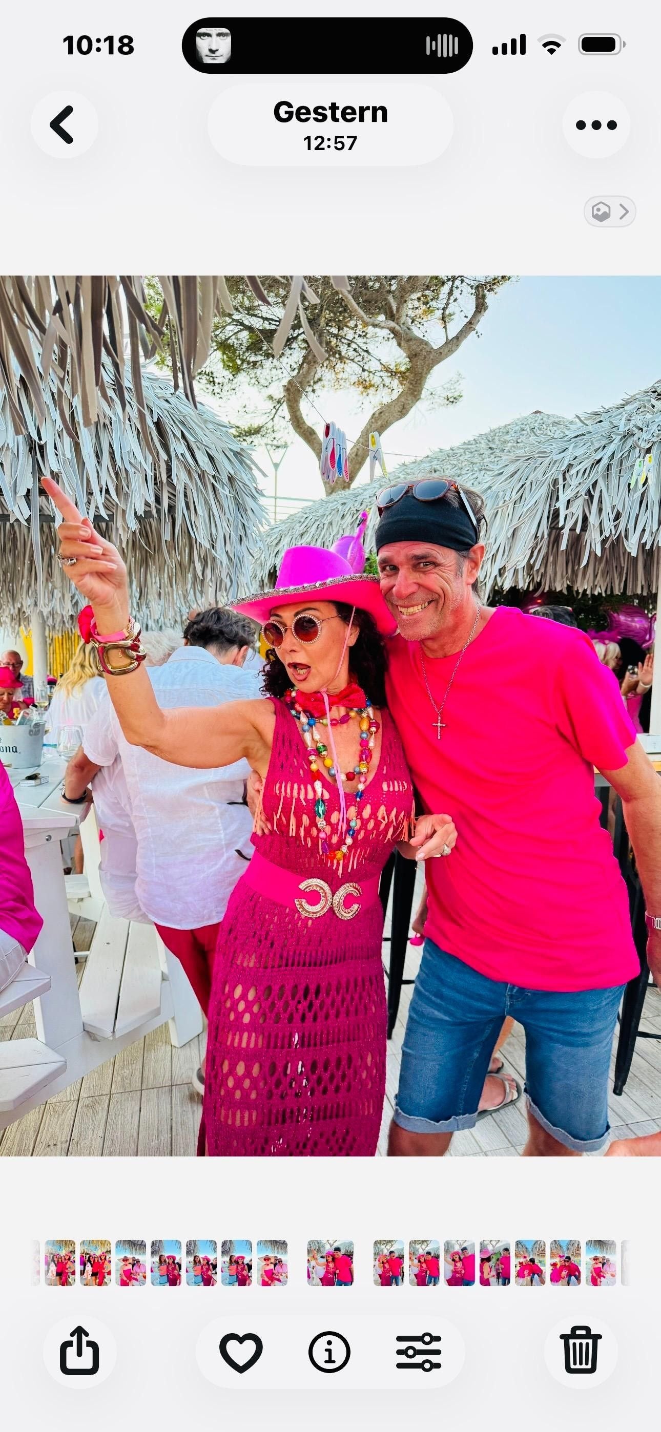 Eine Frau im pinken Outfit und Hut posiert lachend mit einem Mann im pinken T-Shirt.