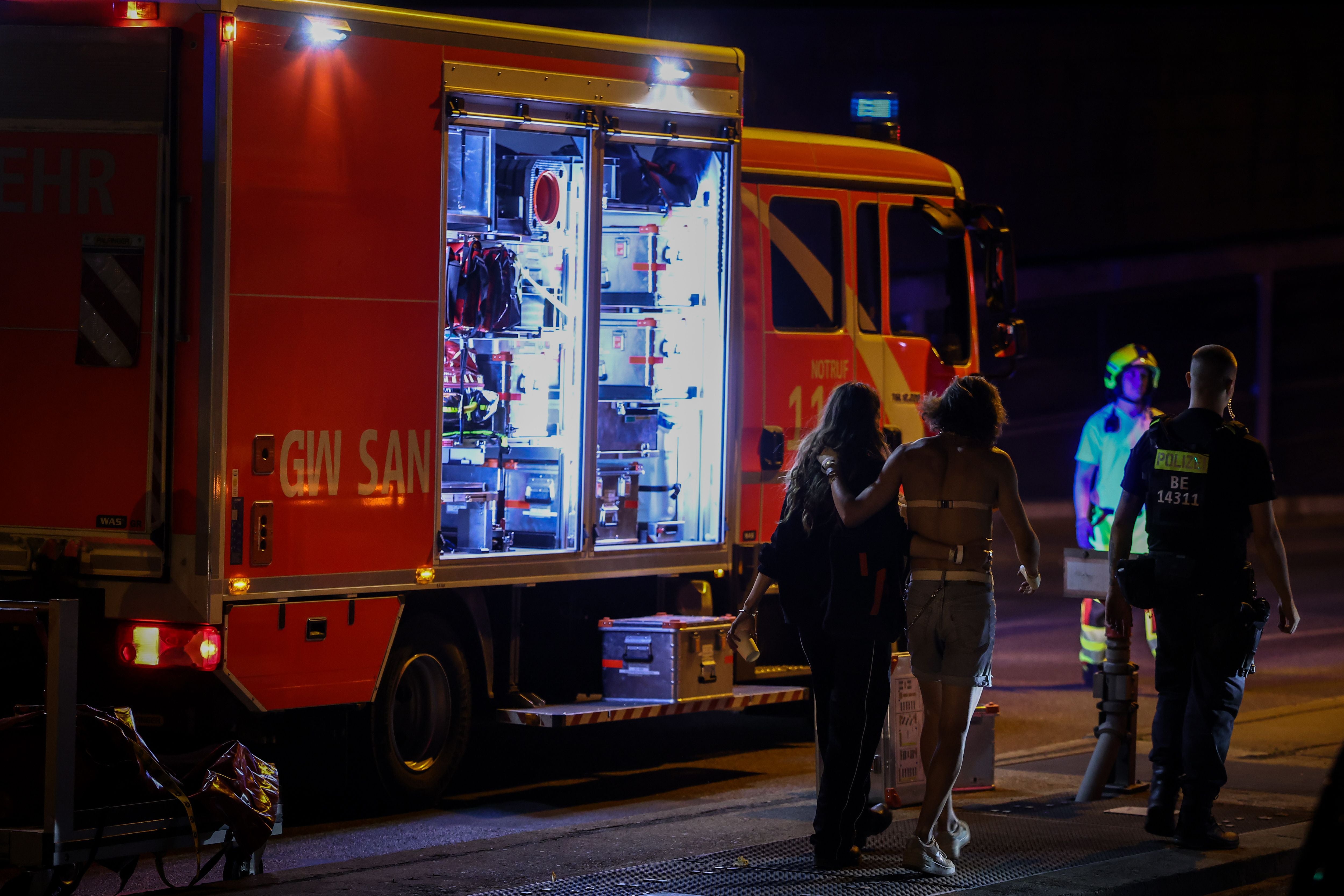 Ein Rettungswagen mit geöffneter Tür, Einsatzkräfte und Verletzte bei Nacht an einem Einsatzort.