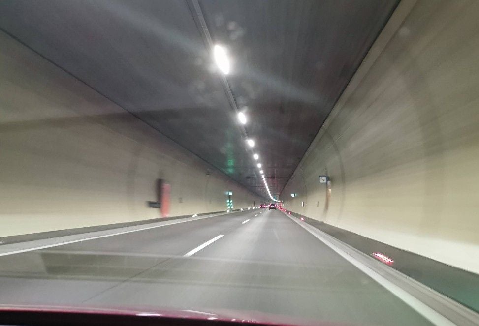 Blick aus einem Auto in den beleuchteten Pfändertunnel mit mehreren Fahrspuren.