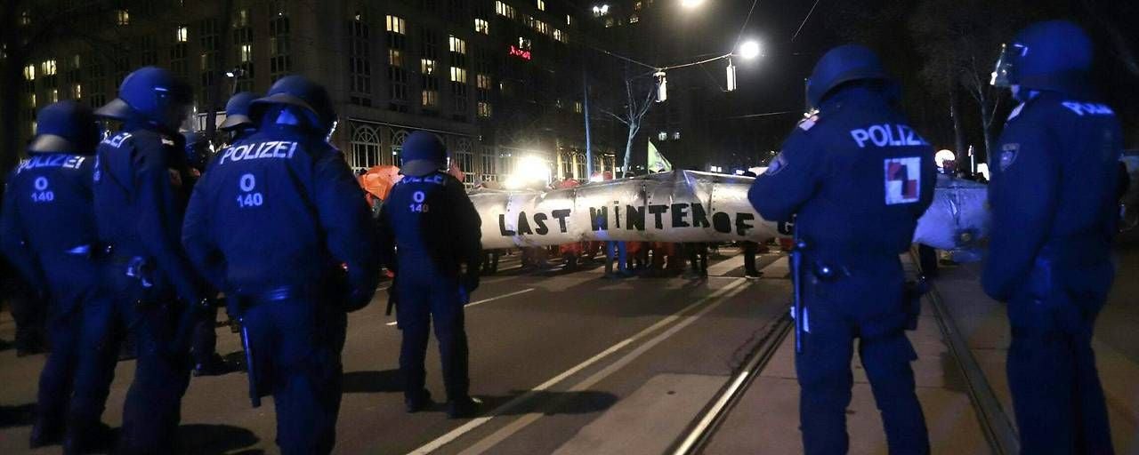 Polizisten stehen nachts bei einer Klima-Demo in Wien vor einem Banner mit der Aufschrift „LAST WINTER OF“.