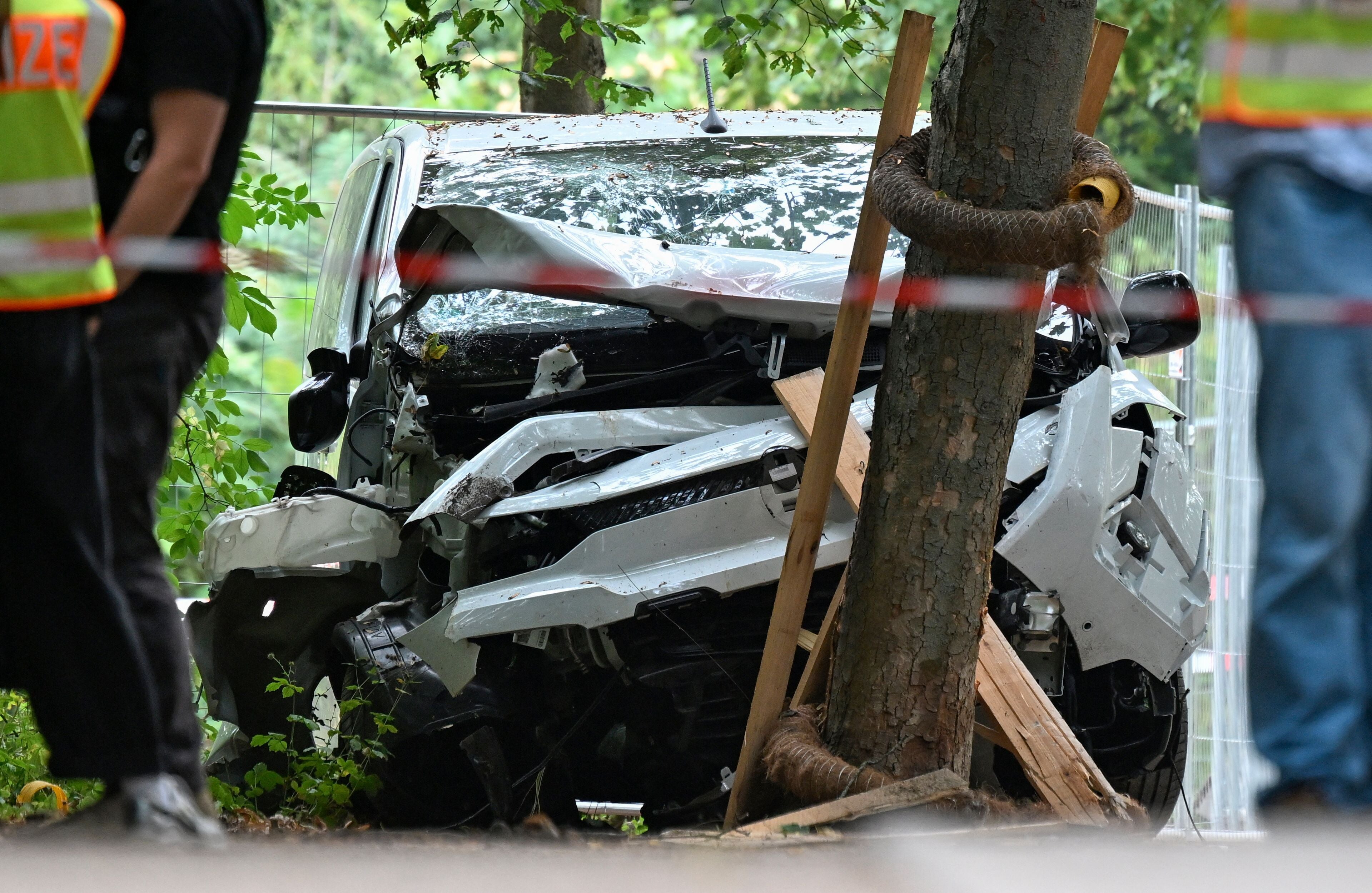 Stark beschädigtes Auto steht nach einem Unfall an einem Baum, umgeben von Polizeiabsperrung.