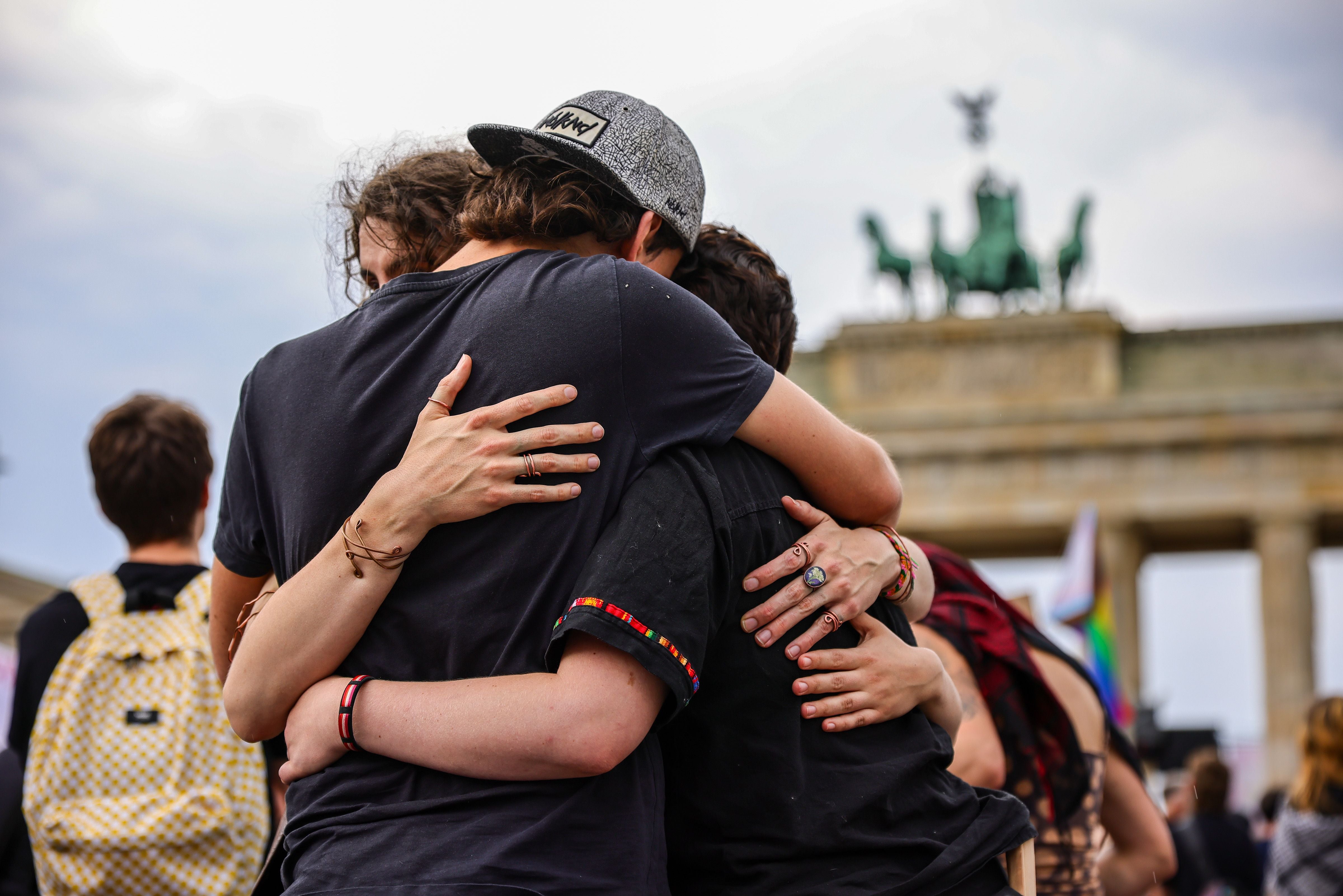 Menschen umarmen sich bei einer Gedenkveranstaltung vor dem Brandenburger Tor in Berlin.