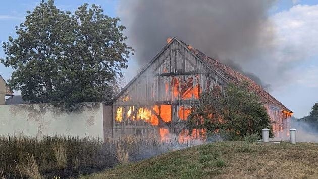 Ein Stadl steht in Flammen, aus dem Dach steigt dichter Rauch auf.
