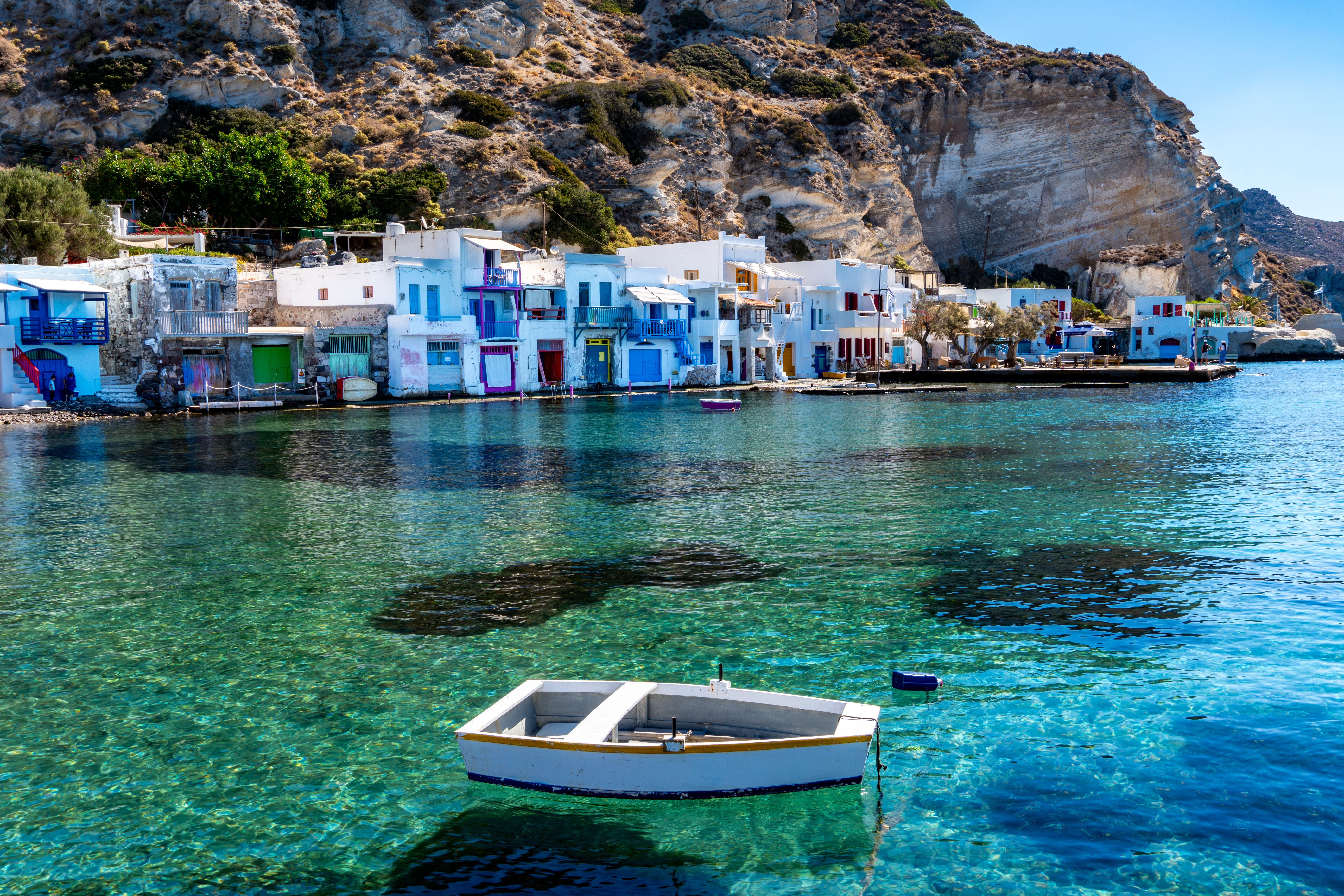 Bunte Häuser am Wasser und ein Boot im klaren Meer im Fischerdorf Klima auf Milos, Griechenland.