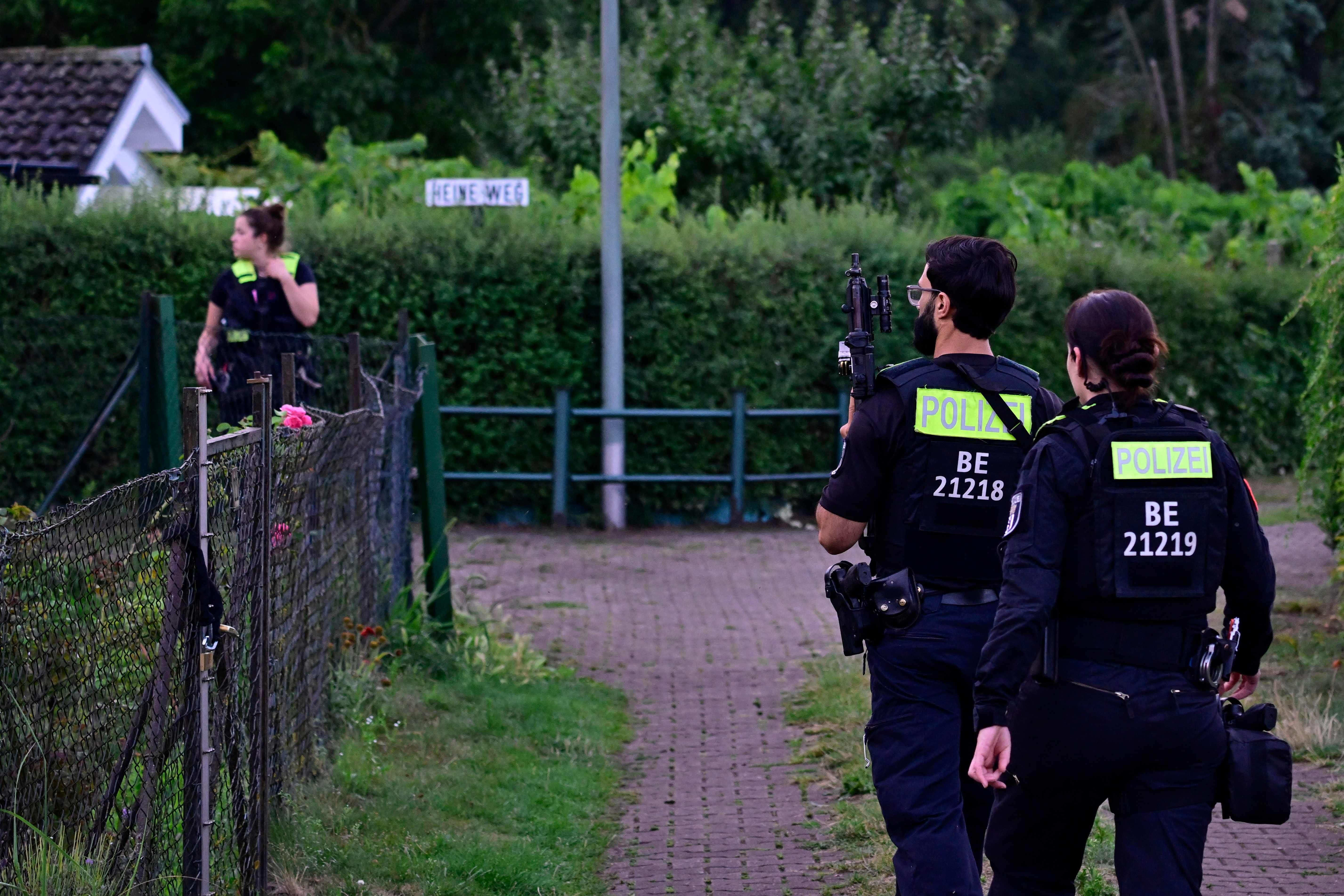 Drei Polizisten mit Schutzwesten in einer Gartenanlage in Berlin-Spandau.