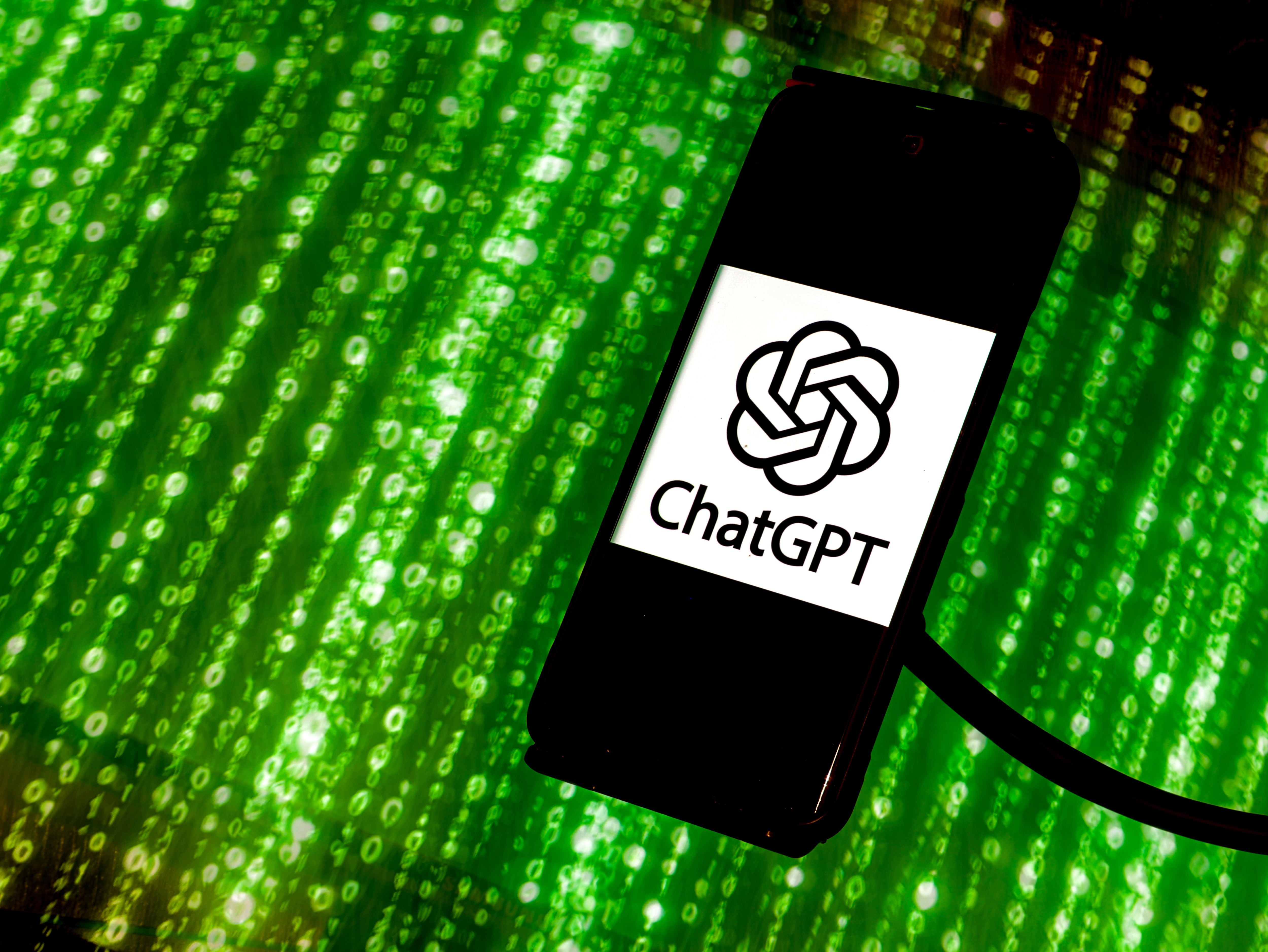 Ein Smartphone mit ChatGPT-Logo liegt vor grünem Hintergrund mit Zahlen im Matrix-Stil.