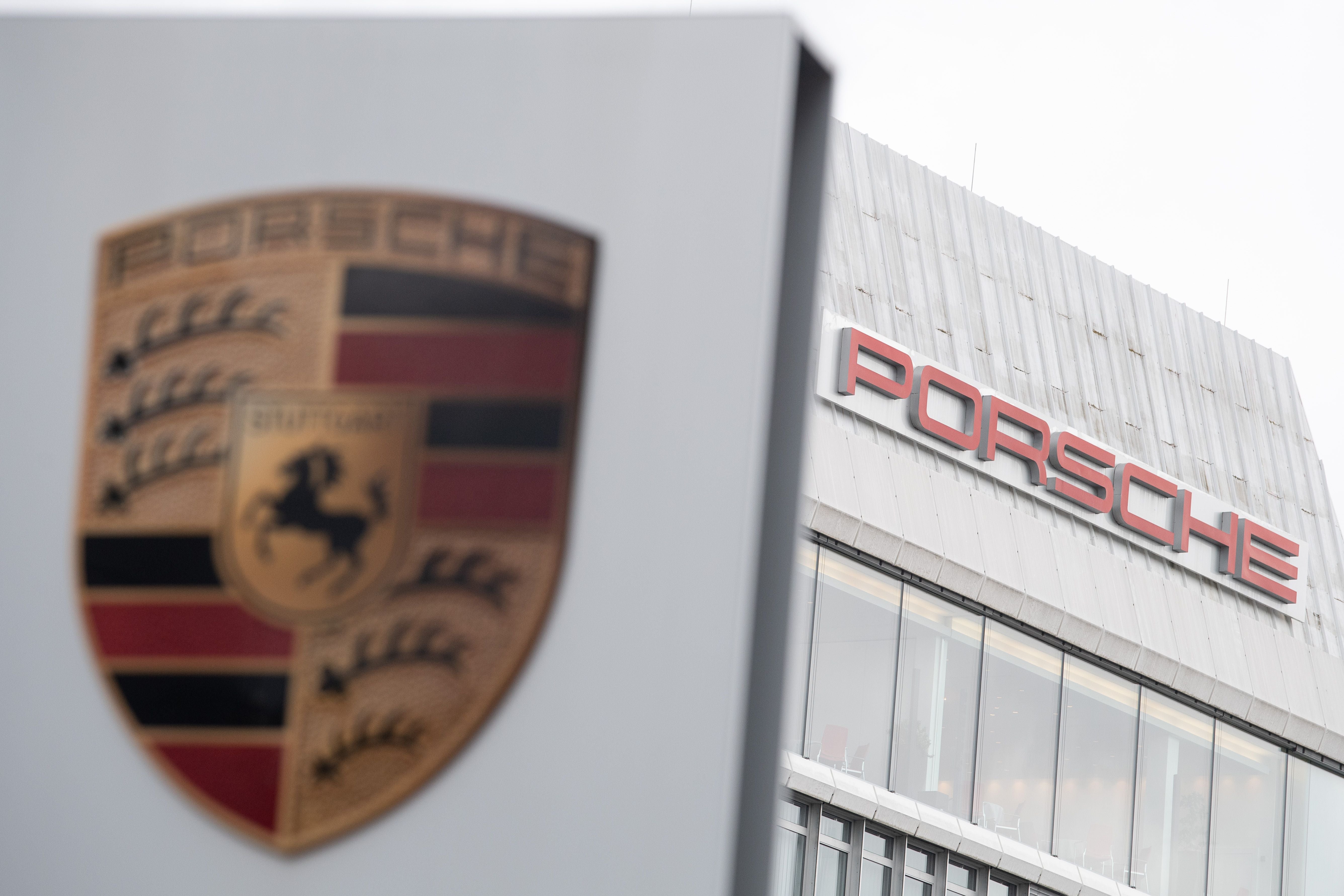Das Porsche-Logo im Vordergrund, dahinter der Schriftzug "Porsche" am Werksgebäude.