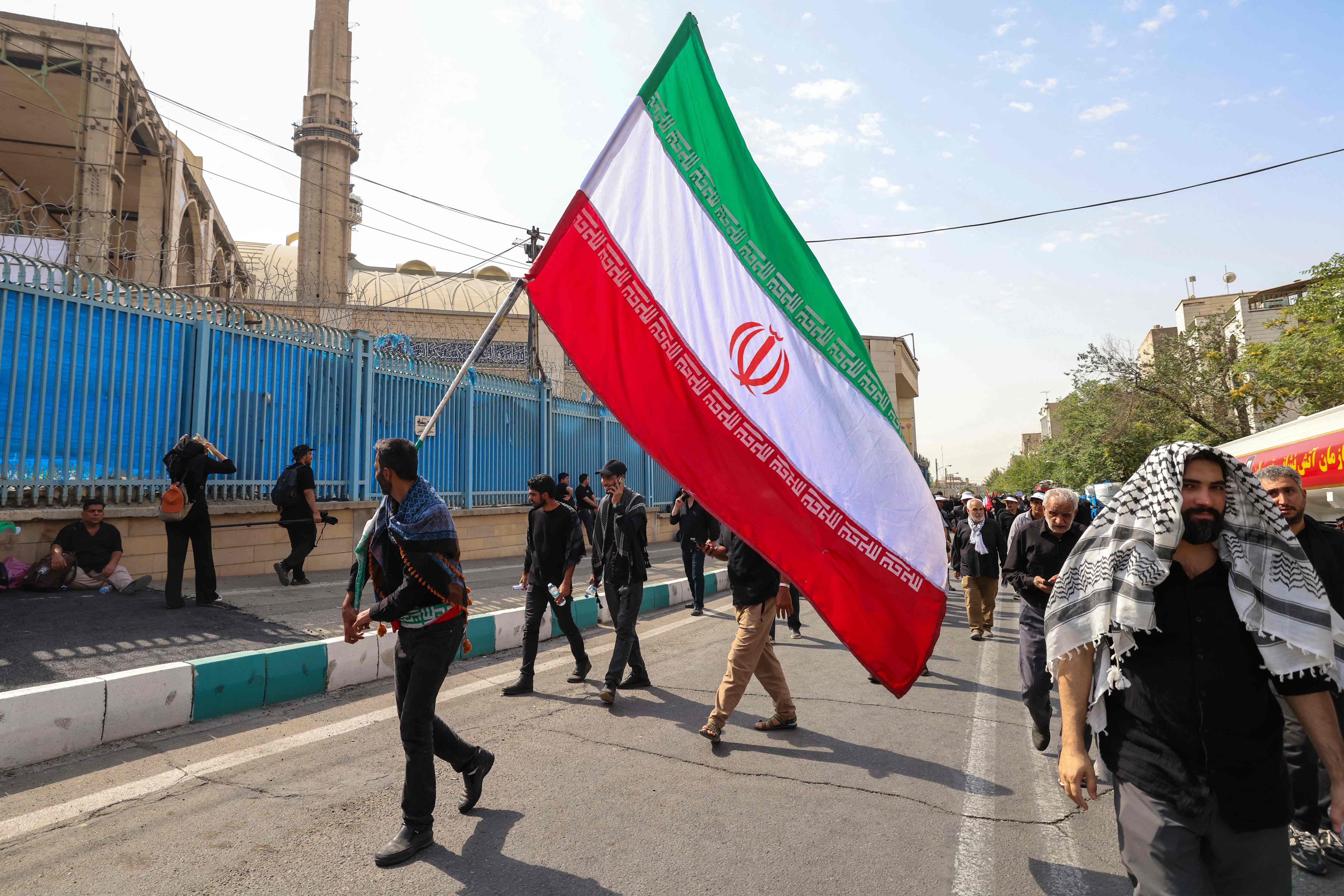 Ein Mann schwenkt eine große iranische Flagge bei einer Trauerprozession in Teheran.