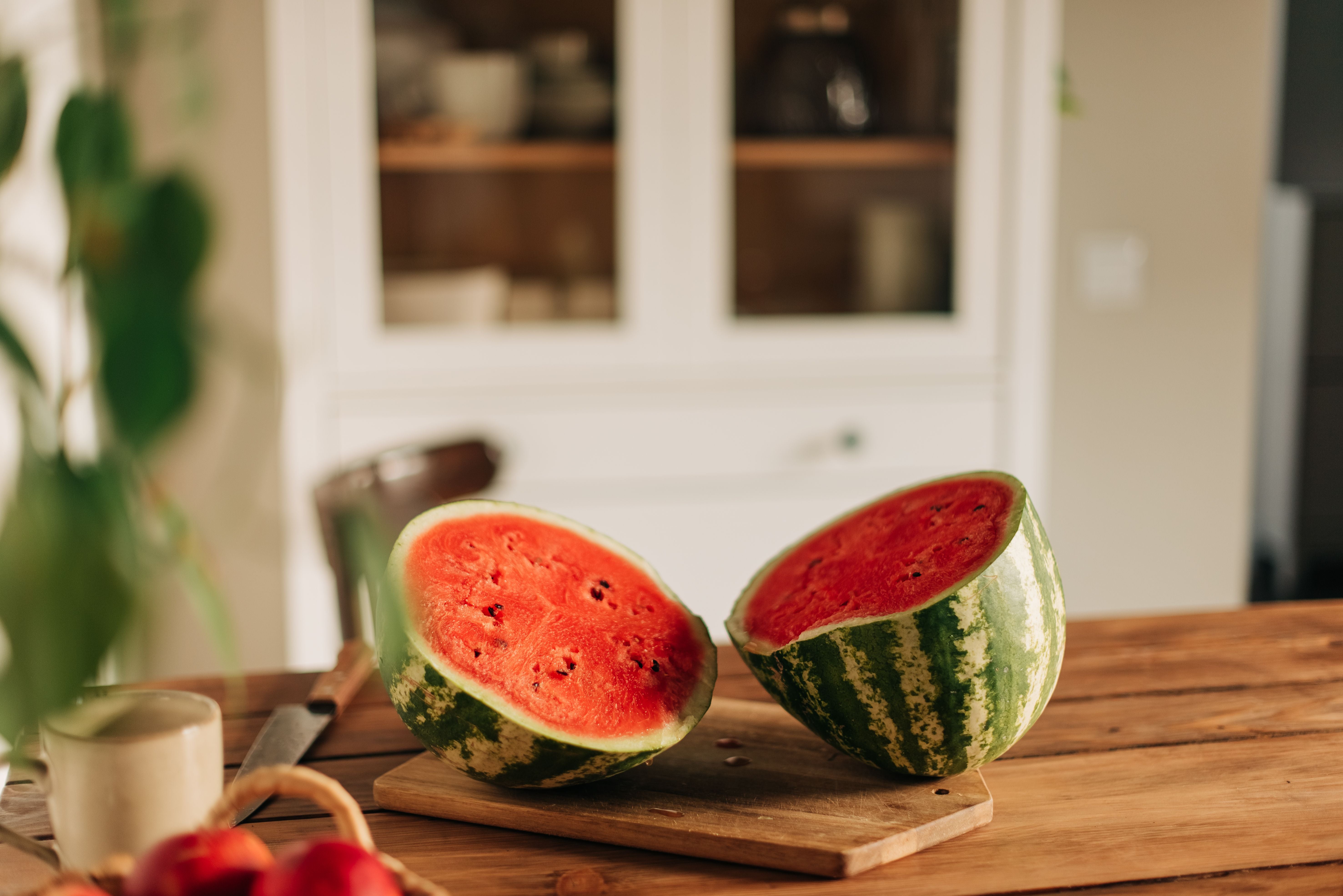 Halbierte Wassermelone liegt auf einem Holzbrett in einer gemütlichen Küche.