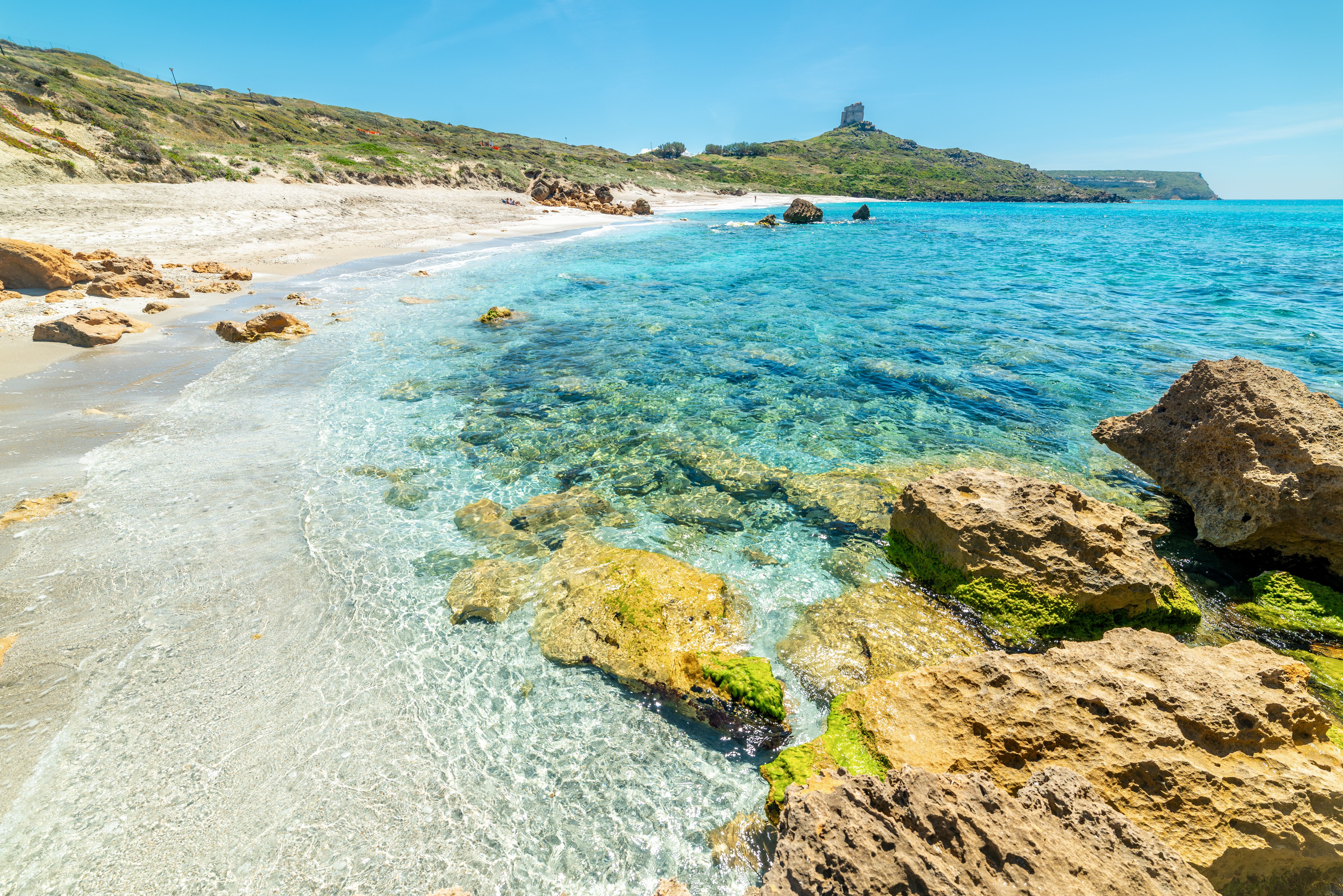 Felsige Küste mit türkisfarbenem Wasser bei San Giovanni di Sinis, Sardinien, an einem sonnigen Tag.