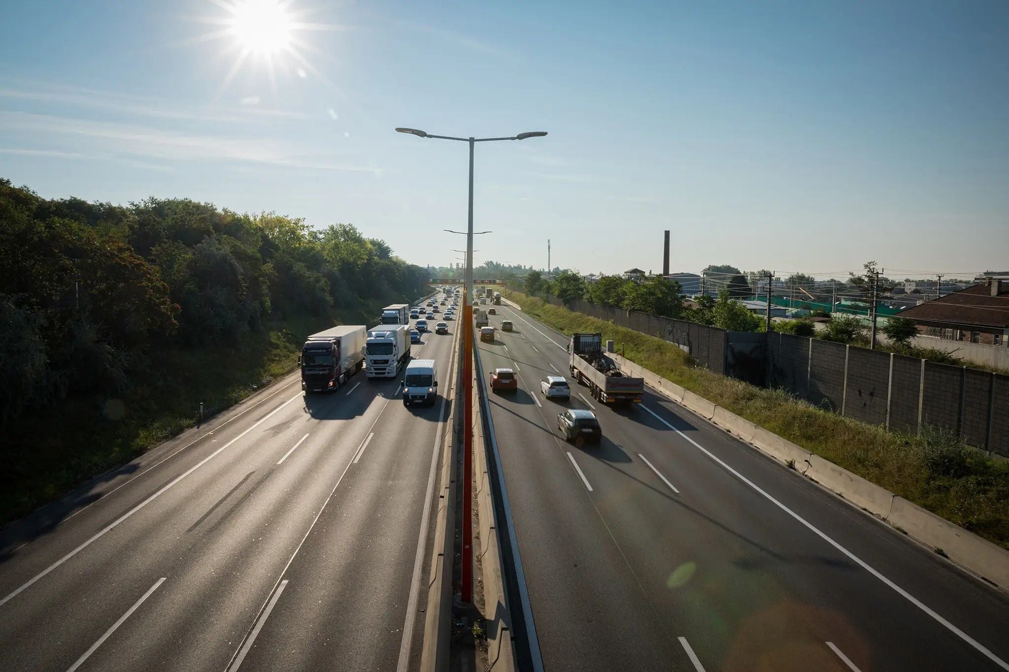 Autos und Lkw fahren bei Sonnenschein mit hohem Tempo auf der Autobahn A1.