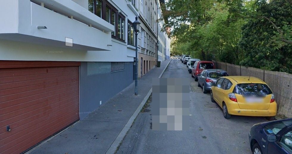Enger Straßenabschnitt mit parkenden Autos und Bäumen entlang der Zahnradbahnstraße.